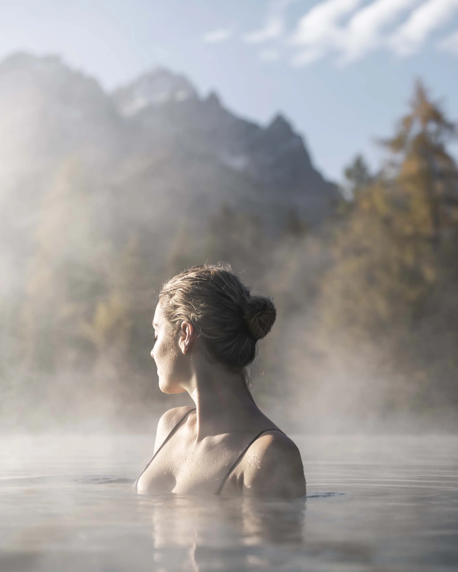 A hideaway for your exclusive holiday in Val Pusteria/Pustertal Woman relaxing in hot thermal water with misty mountain landscape background