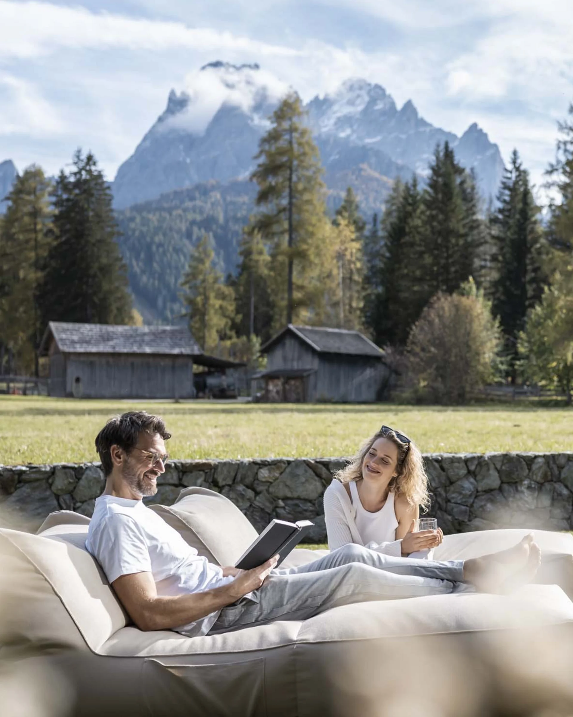 A hideaway for your exclusive holiday in Val Pusteria/Pustertal Couple relaxing on sofa in garden with mountains and houses in the background
