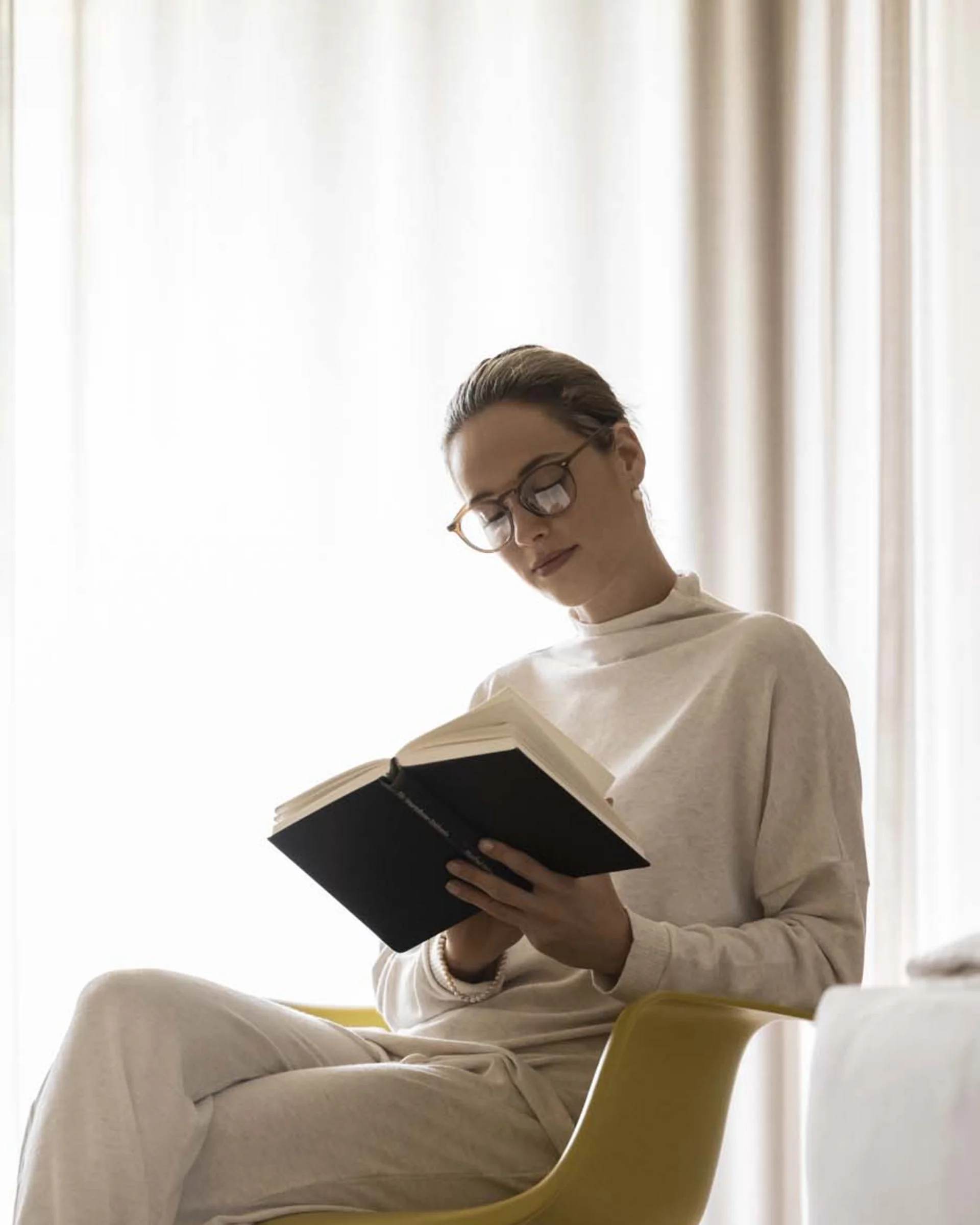 A hideaway for your exclusive holiday in Val Pusteria/Pustertal Woman reading a book while sitting on a yellow rocking chair in the living room