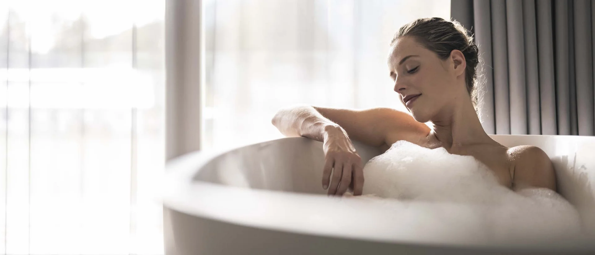 Hotel Monika: soothing day spa in Val Pusteria/Pustertal valley Woman relaxing in a bathtub filled with bubbles