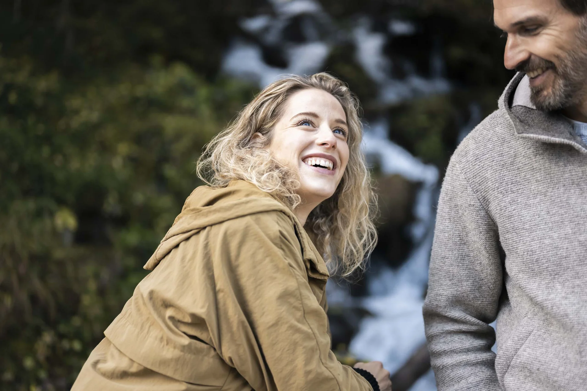 Hotel Monika in Sexten: Wohlbefinden inmitten der Dolomiten Frau lacht mit Mann draußen vor natürlichem Hintergrund