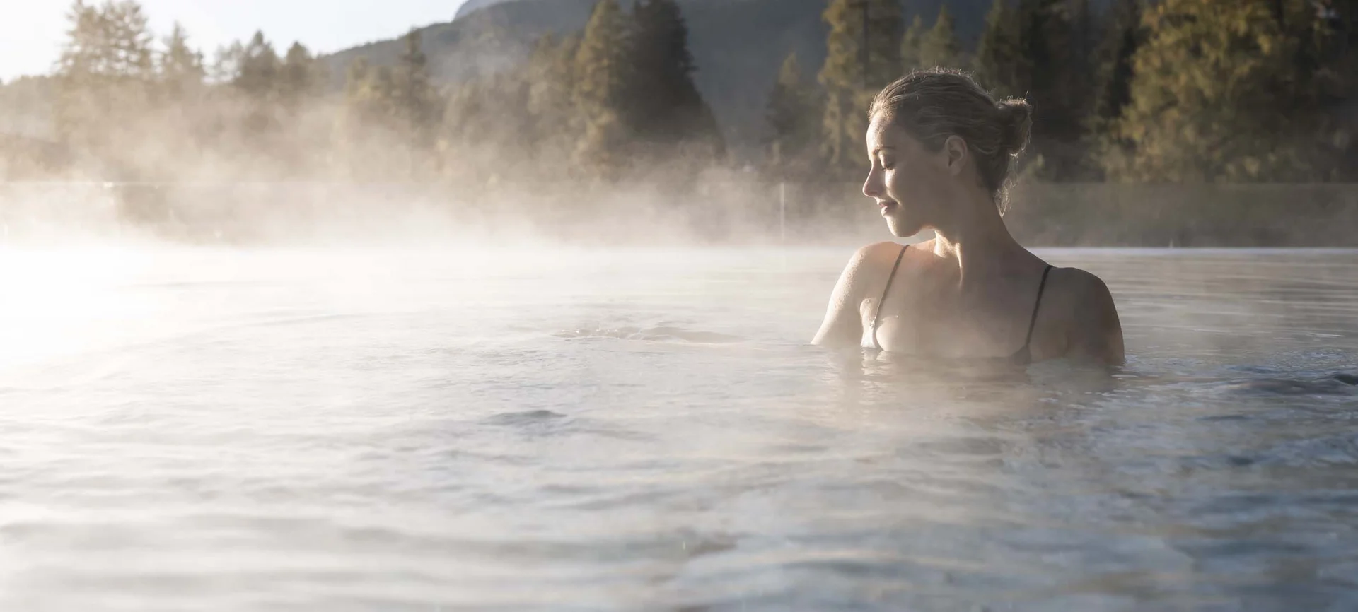 Hotel Monika in the Dolomites – with pools and spa area Woman relaxing in hot spring pool with mountain scenery in background