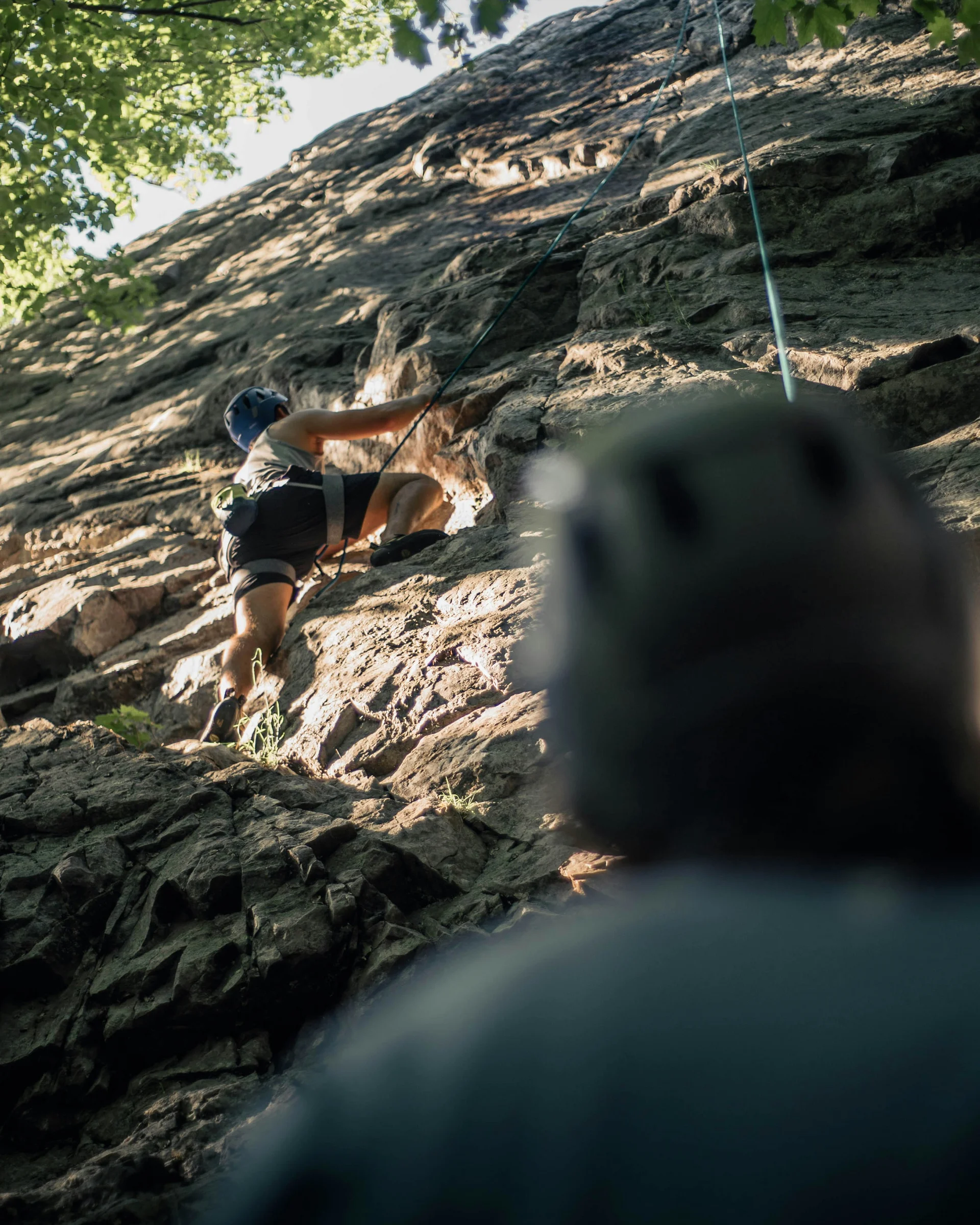 Summer in the mountains. At your hiking hotel in the Dolomites. Person climbing a rock face while another person belays from below