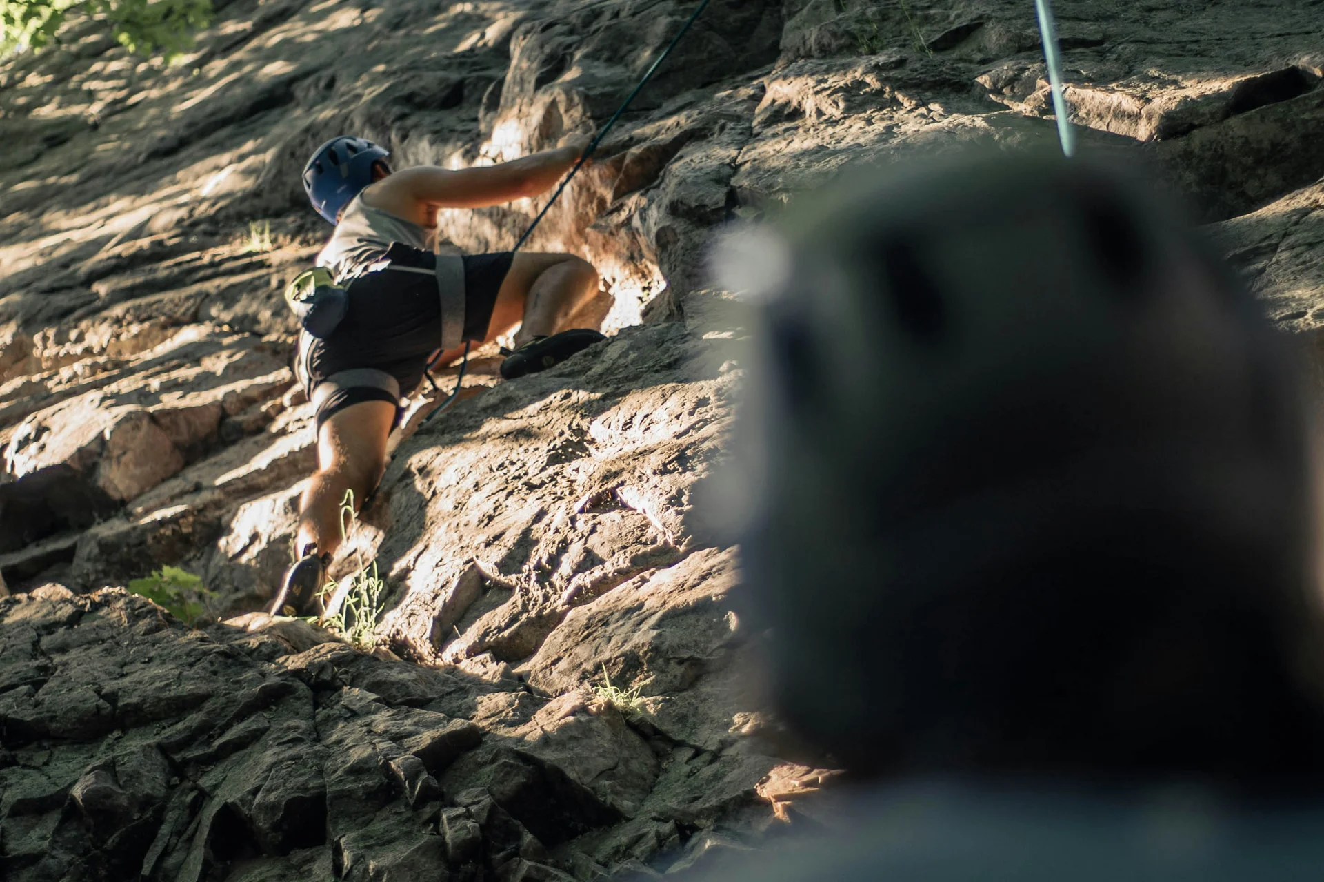 Sommer in den Bergen. In Ihrem Wanderhotel in den Dolomiten. Person klettert an einem Felsen, eine zweite Person sichert von unten