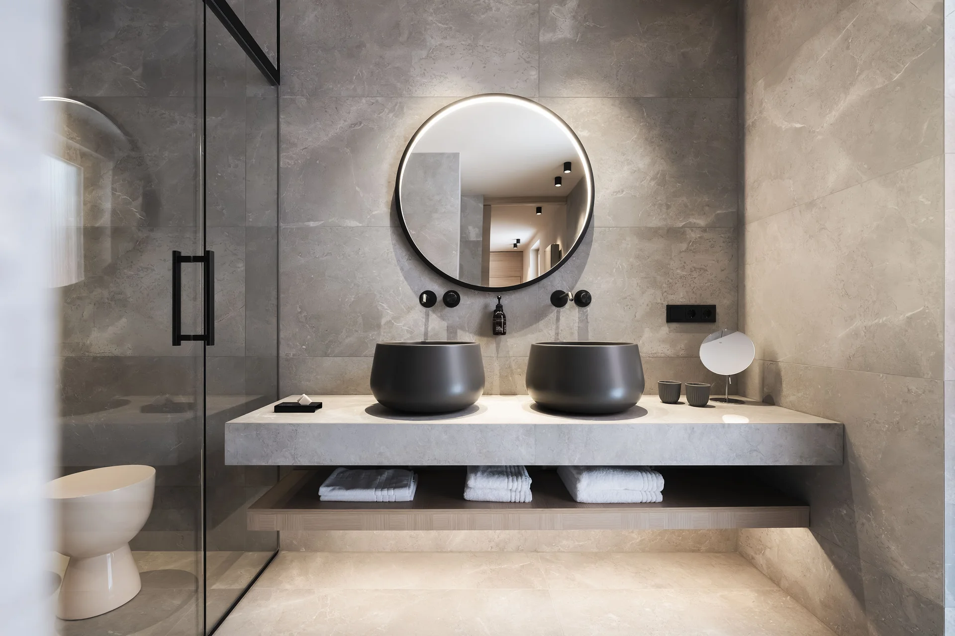 Hotel Monika in Sexten: Wohlbefinden inmitten der Dolomiten Modernes Badezimmer mit zwei schwarzen Waschbecken und ovalem Spiegel