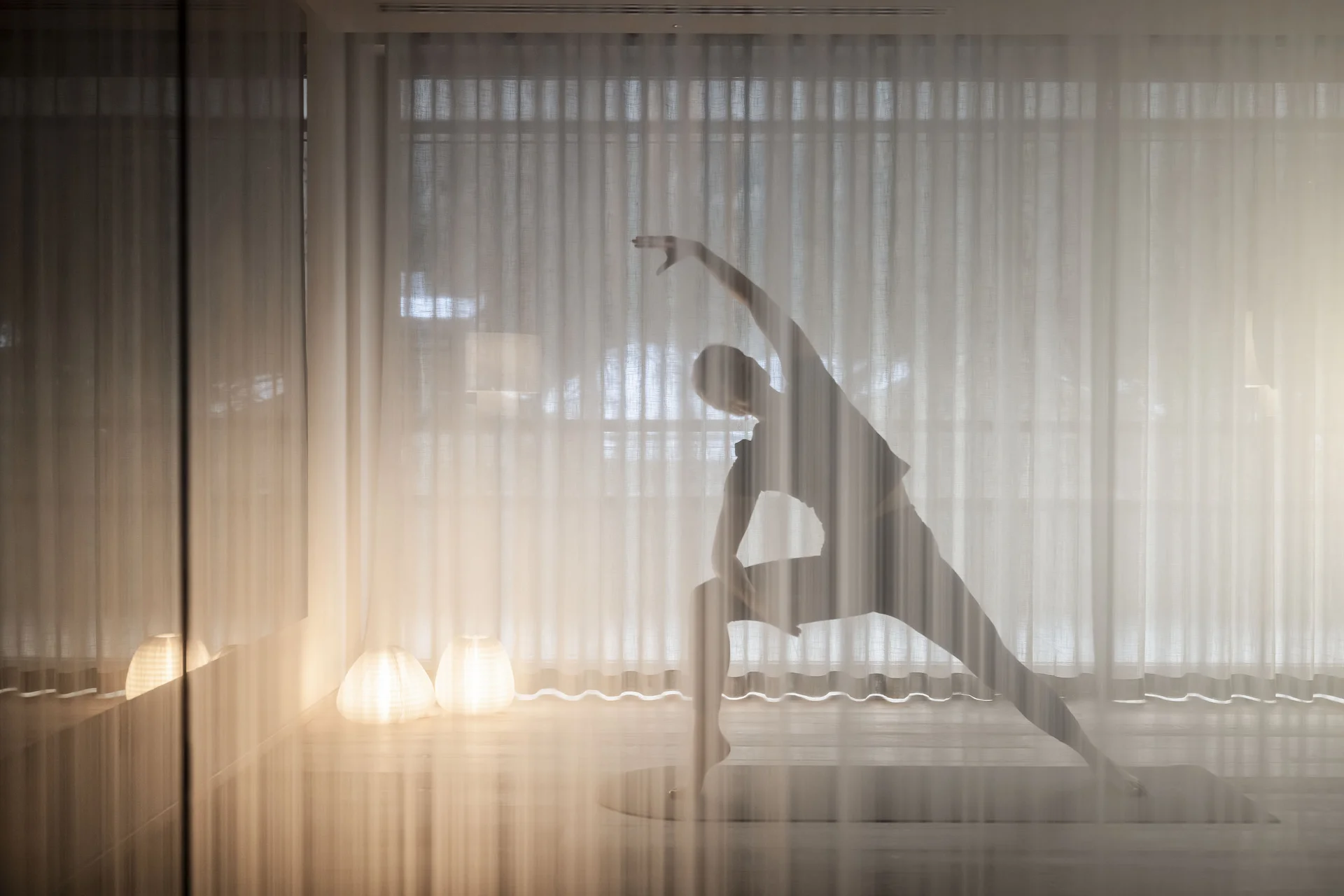 Hotel Monika: wohltuender Day Spa im Pustertal Silhouette beim Yoga-Stretching hinter einem durchsichtigen Vorhang