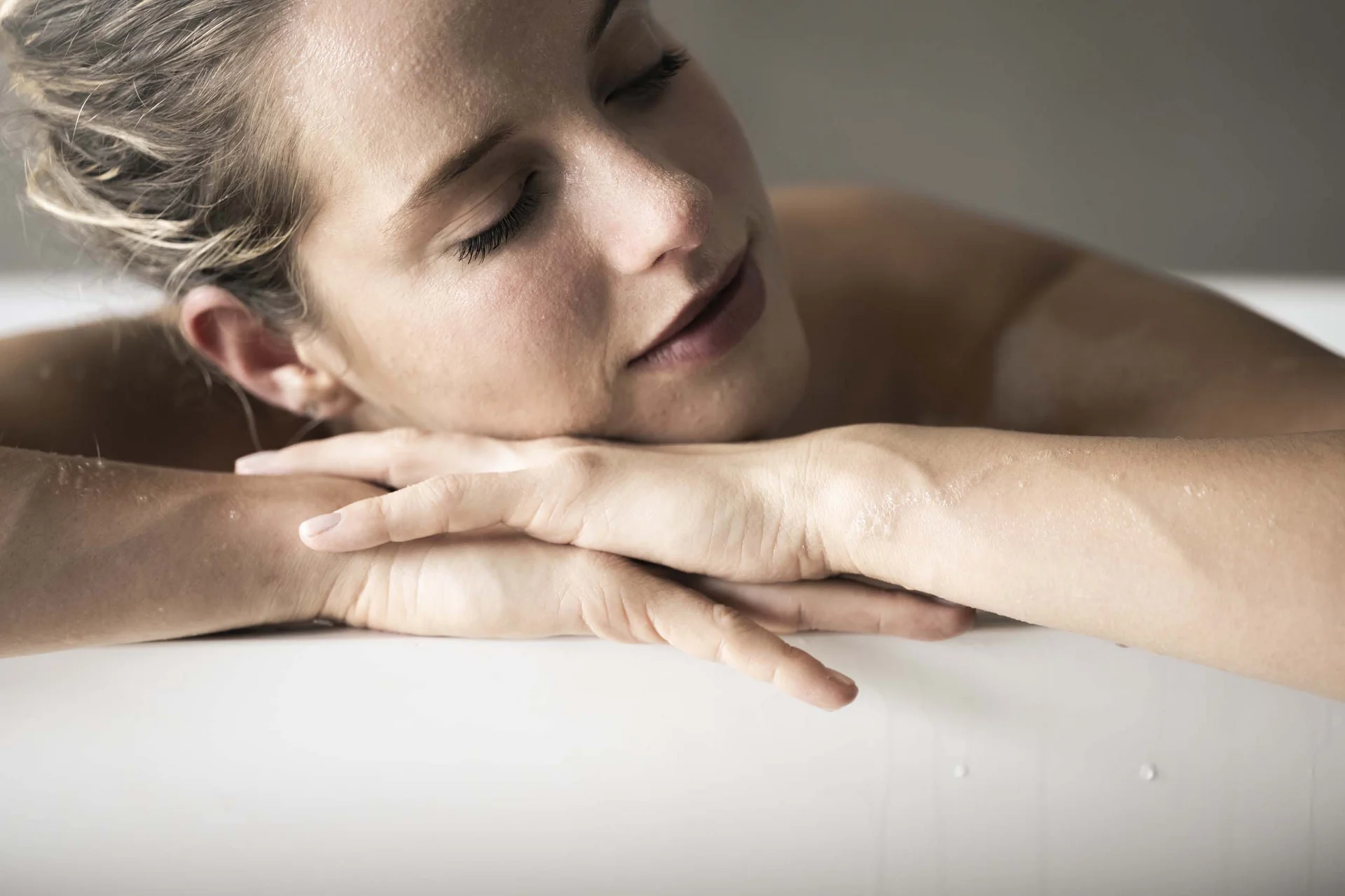 Hotel Monika in Sexten: Wohlbefinden inmitten der Dolomiten Frau entspannt sich mit geschlossenen Augen auf einer weißen Oberfläche