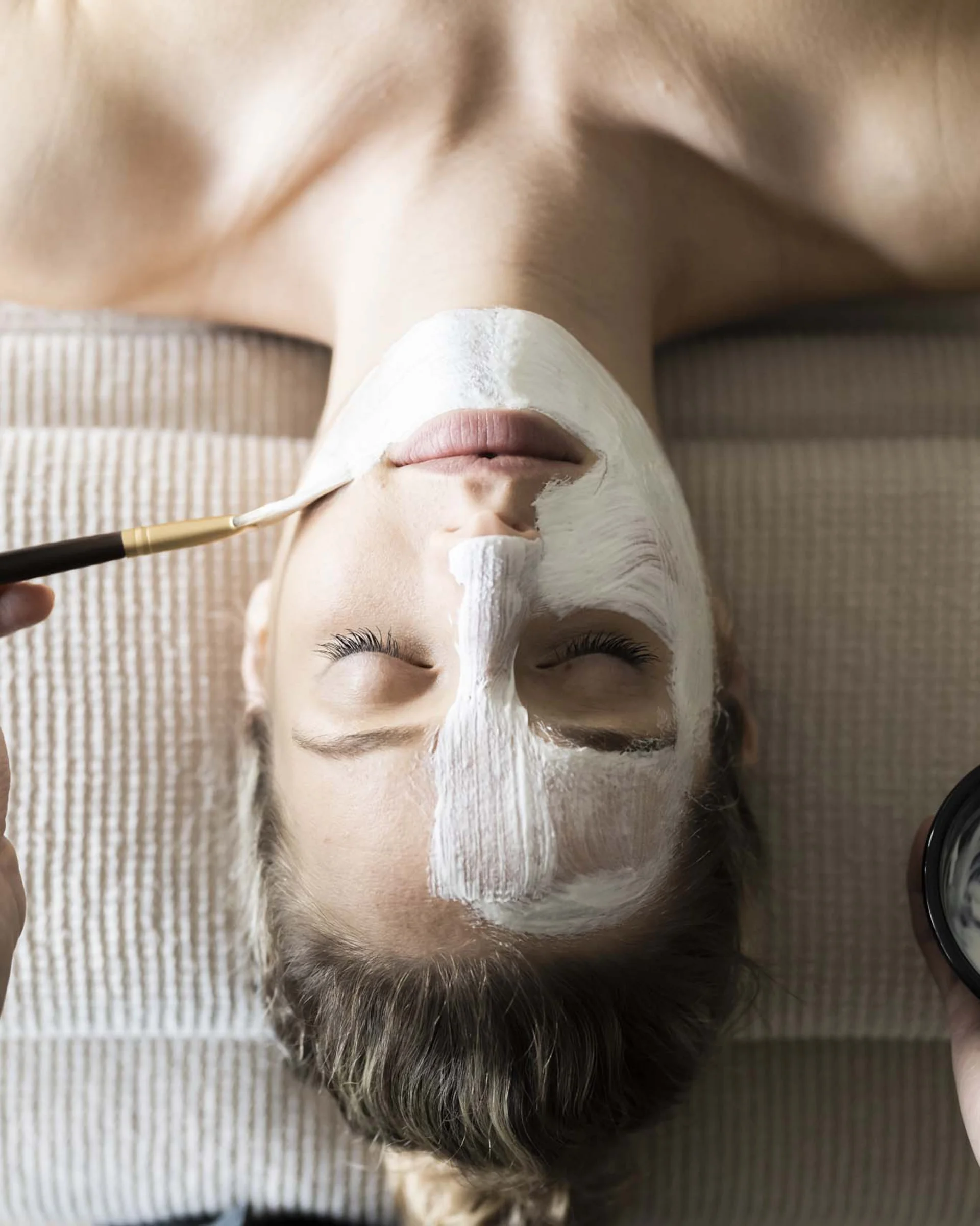 A new dimension of well-being: your wellness hotel in Sexten Woman receiving a facial mask applied by a person