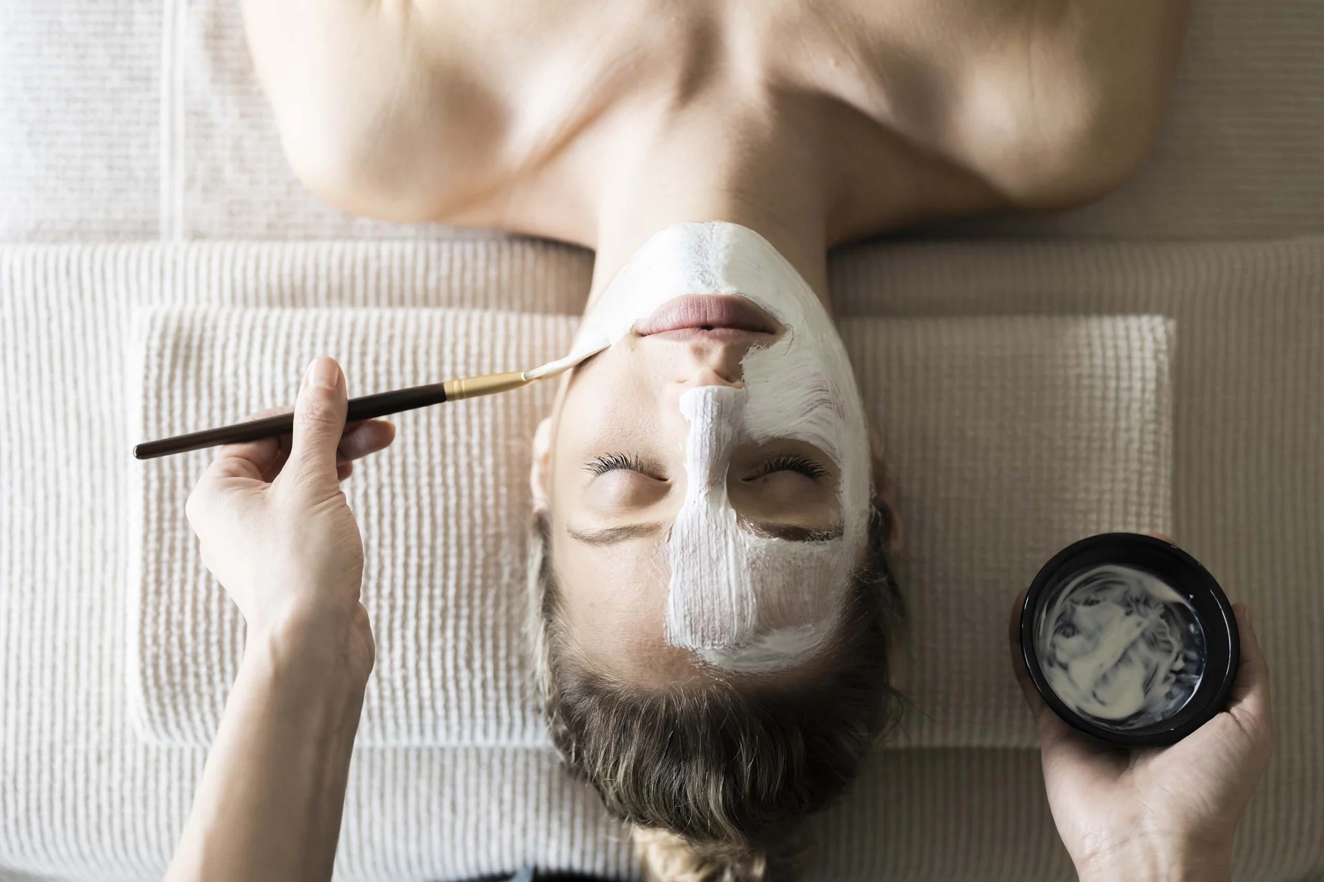 Hotel Monika in Sexten: Wohlbefinden inmitten der Dolomiten Frau erhält eine Gesichtsmaske, die von einer Person aufgetragen wird