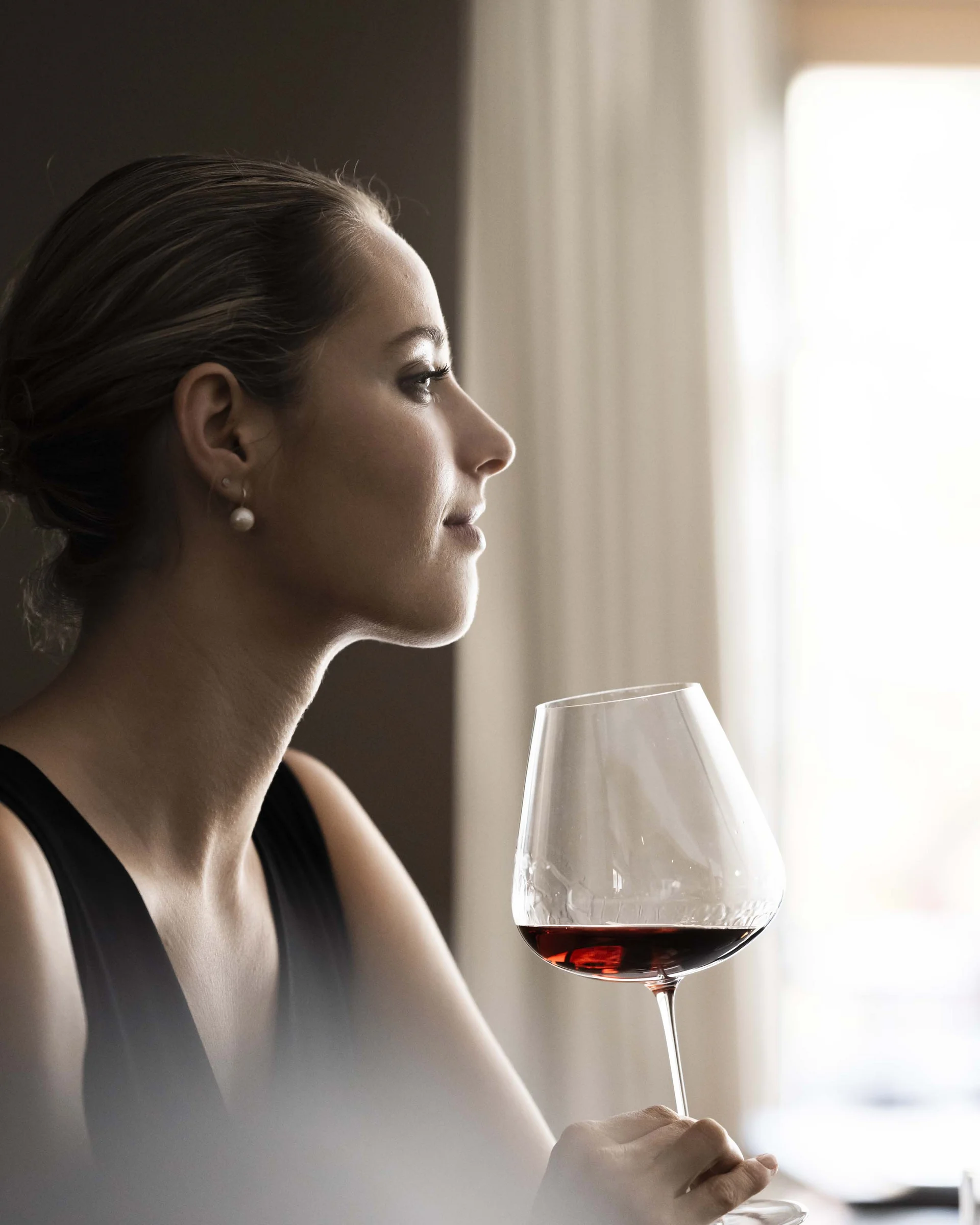 Hotel Monika: a new dimension of luxury Elegant woman holding a glass of red wine looking out the window
