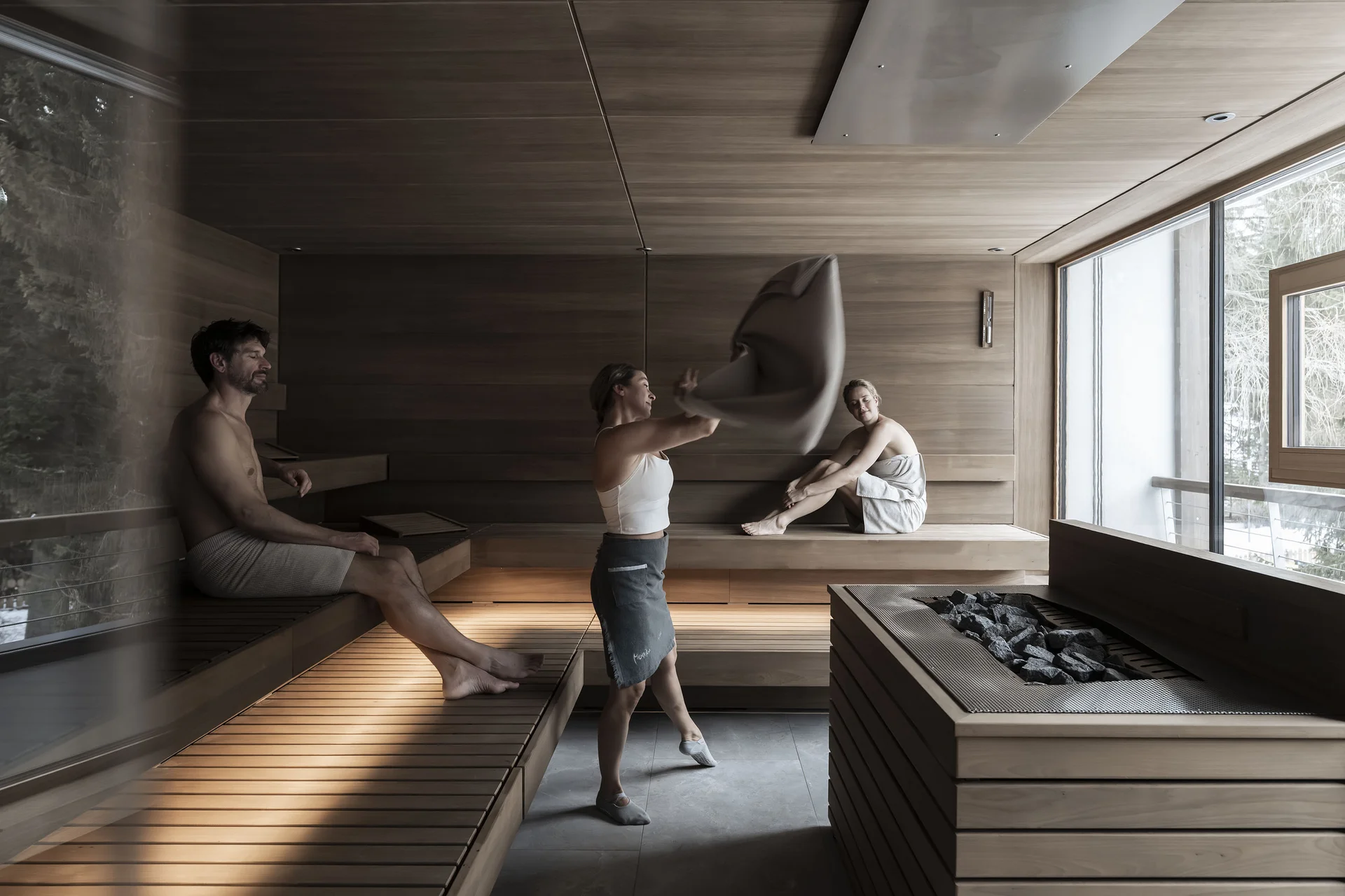 Saunalandschaft Drei Personen entspannen sich in einer Sauna mit großen Fenstern.