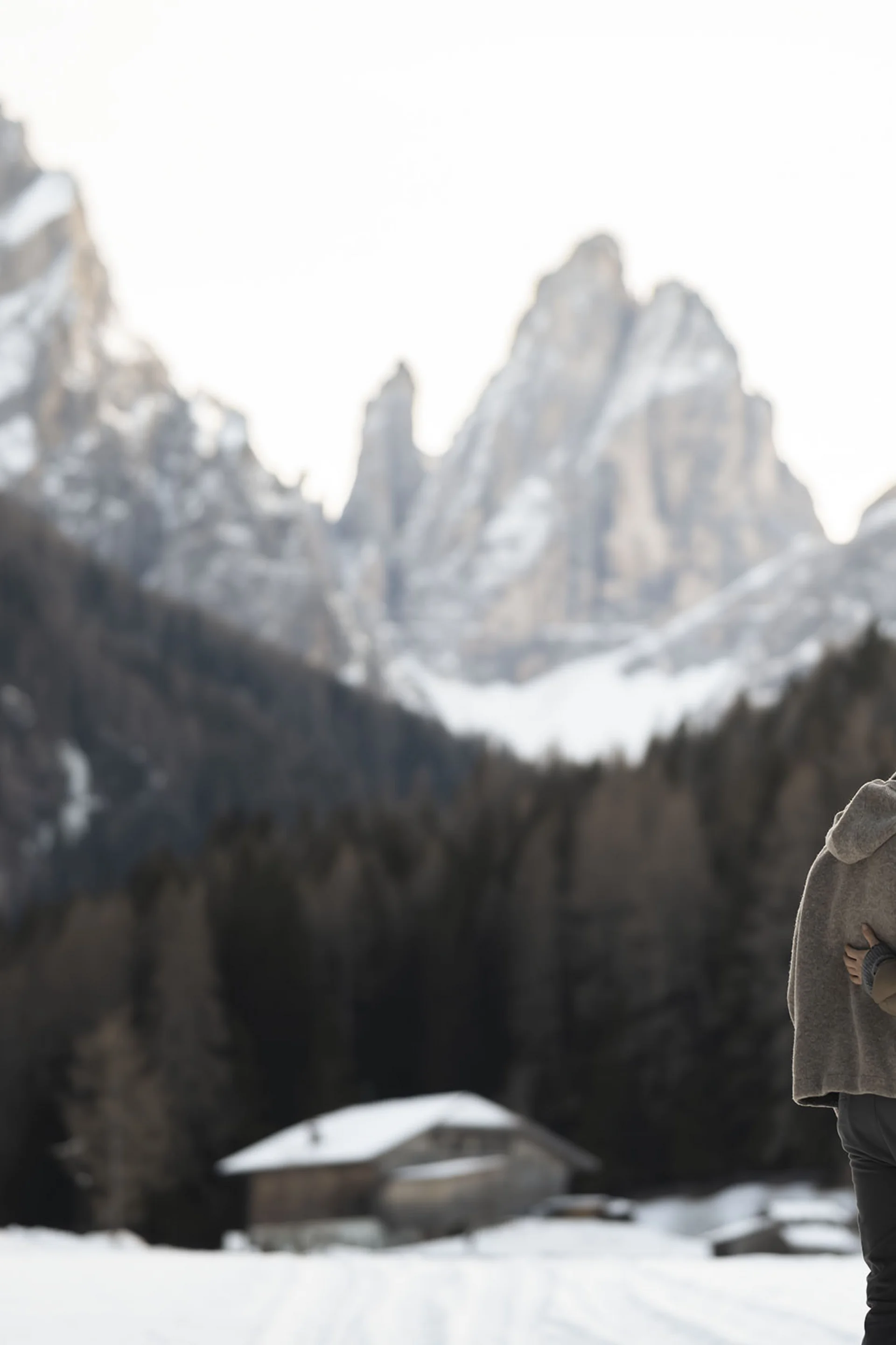 Hotel Monika: eine neue Dimension von Luxus Paar umarmt sich in verschneiter Berglandschaft mit Holzhütten