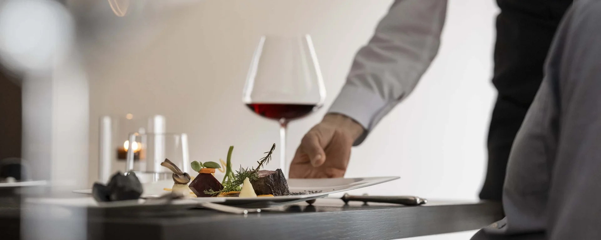 Vacancies at Hotel Monika Waiter serving gourmet dish with red wine at restaurant table
