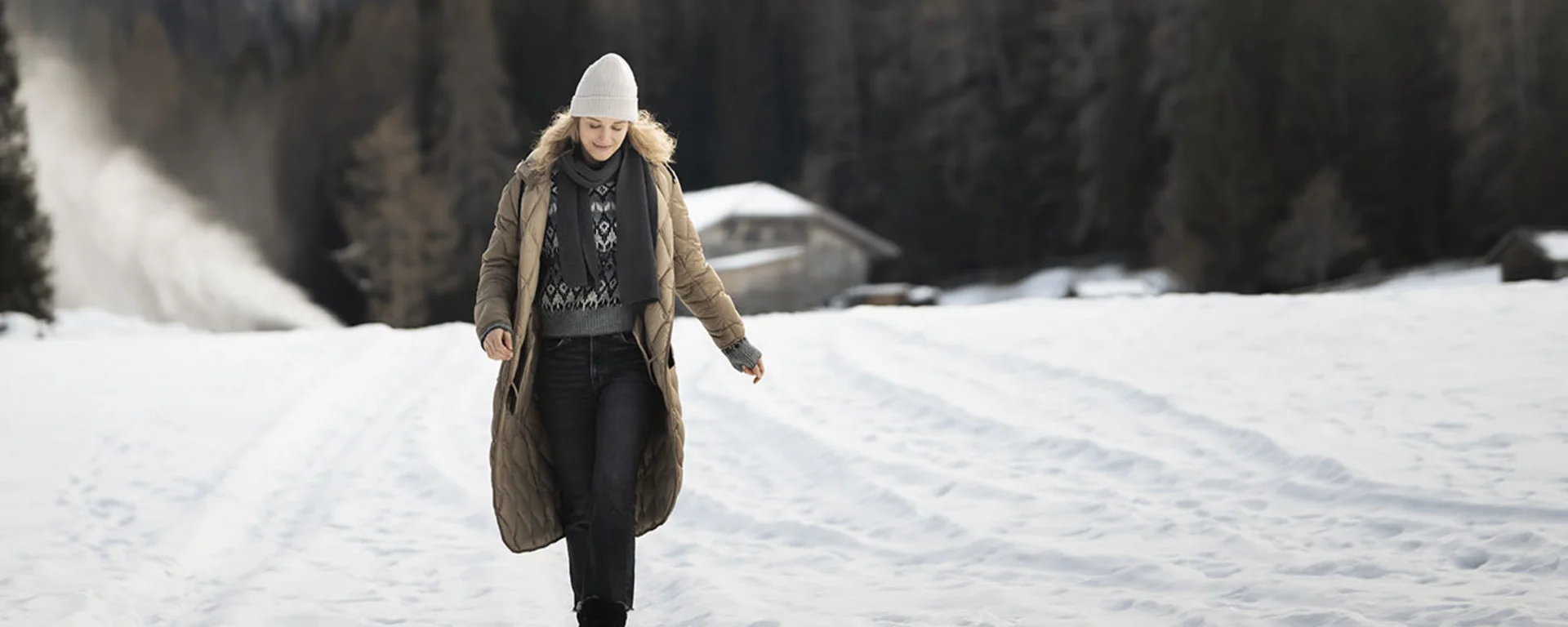 Luxus aus der Natur: Ihr nachhaltiges Hotel in Südtirol Frau in Winterkleidung geht auf schneebedecktem Feld mit Bergen im Hintergrund