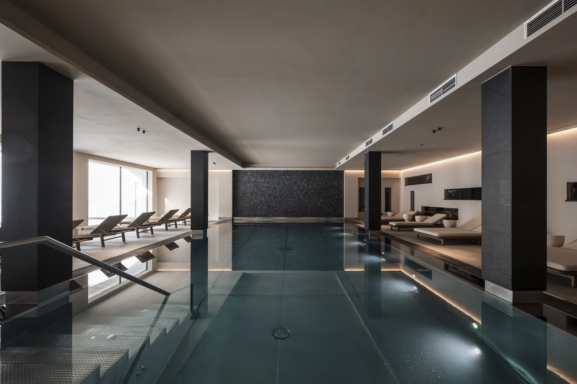Hotel Monika in Sexten: Wohlbefinden inmitten der Dolomiten Moderner, stilvoller Innenpool mit Liegestühlen und gedämpfter Beleuchtung