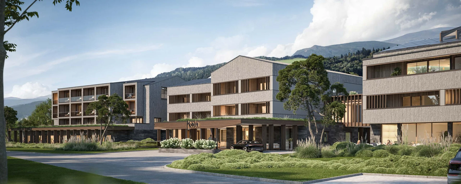 Hotel Monika in Sexten: Wohlbefinden inmitten der Dolomiten Modernes Hotelgebäude umgeben von Grünflächen und Bergen im Hintergrund