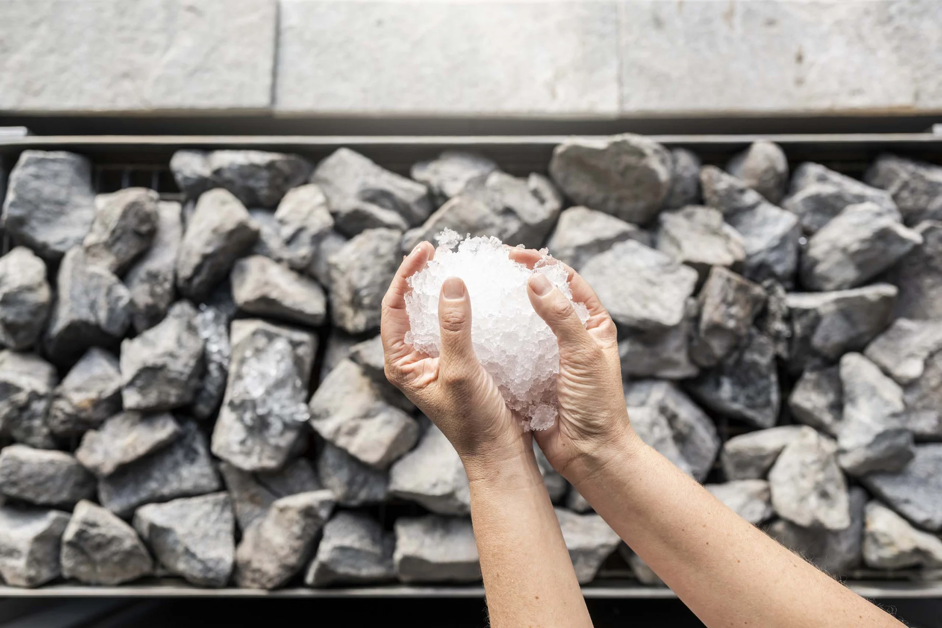 Hotel Monika in Sexten: Wohlbefinden inmitten der Dolomiten Hände halten eine Kugel aus Eis vor einem Steinbruchhintergrund