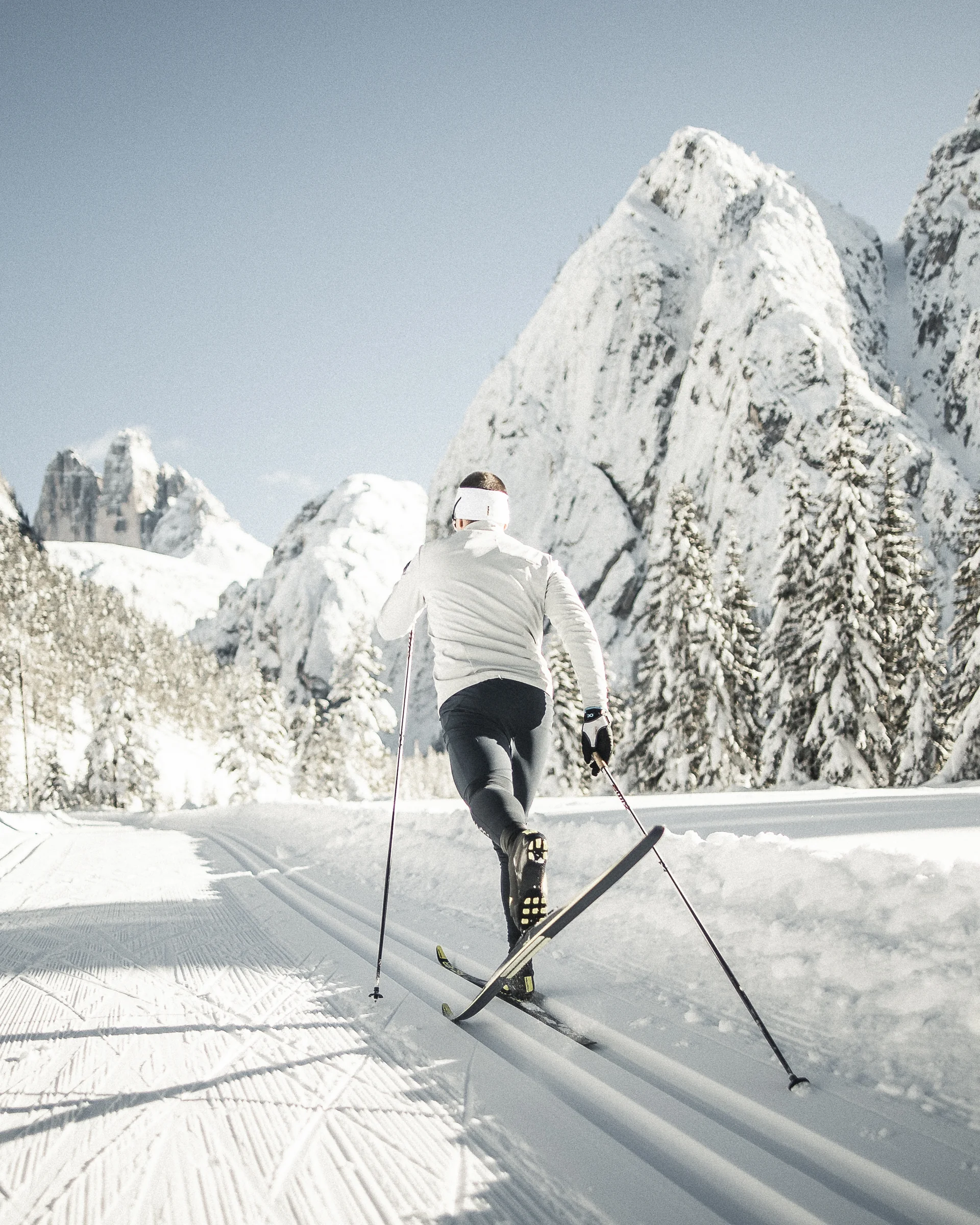 Enriching winter holidays – at our ski hotel in the Dolomites Cross-country skier on snowy trail with snow-covered mountains in background