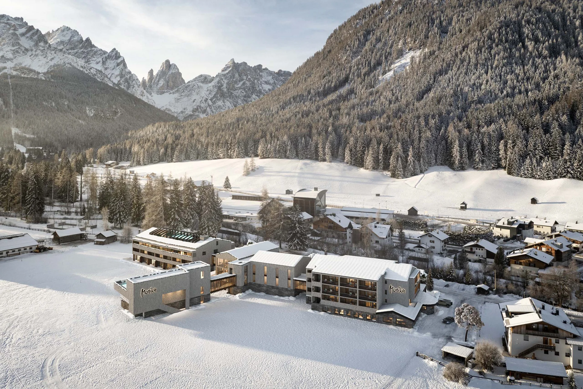 Hotel Monika in Sexten: Wohlbefinden inmitten der Dolomiten Hotel Monika im verschneiten Tal mit Bergen und Wald im Hintergrund