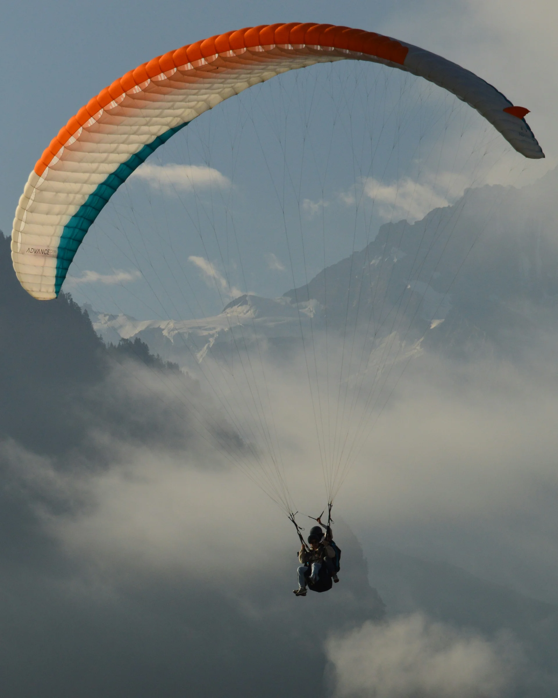 Enriching winter holidays – at our ski hotel in the Dolomites Two people paragliding over foggy mountains