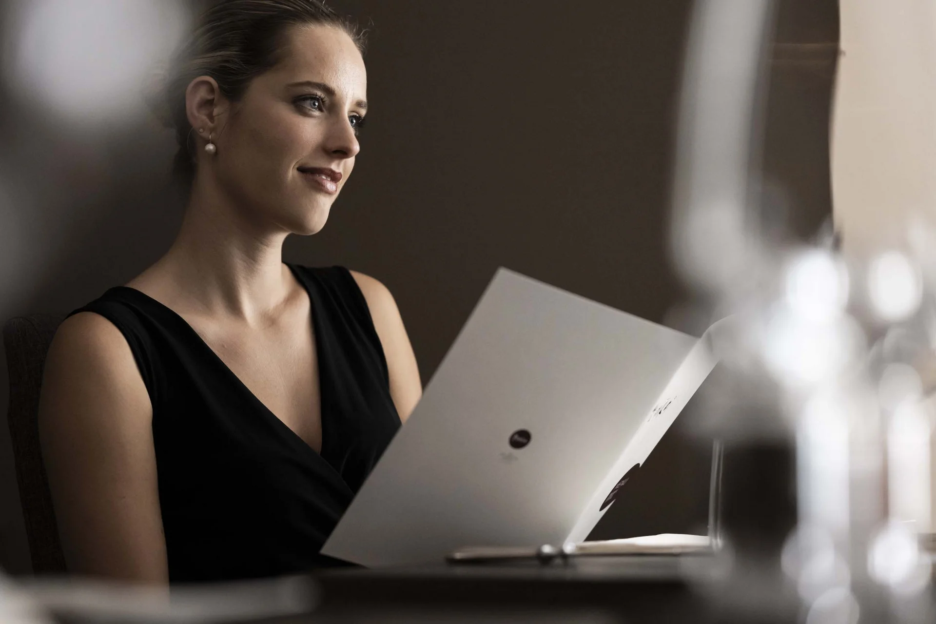 Hotel Monika in Sexten: Wohlbefinden inmitten der Dolomiten Frau in schwarzem Kleid liest Menü in elegantem Restaurant