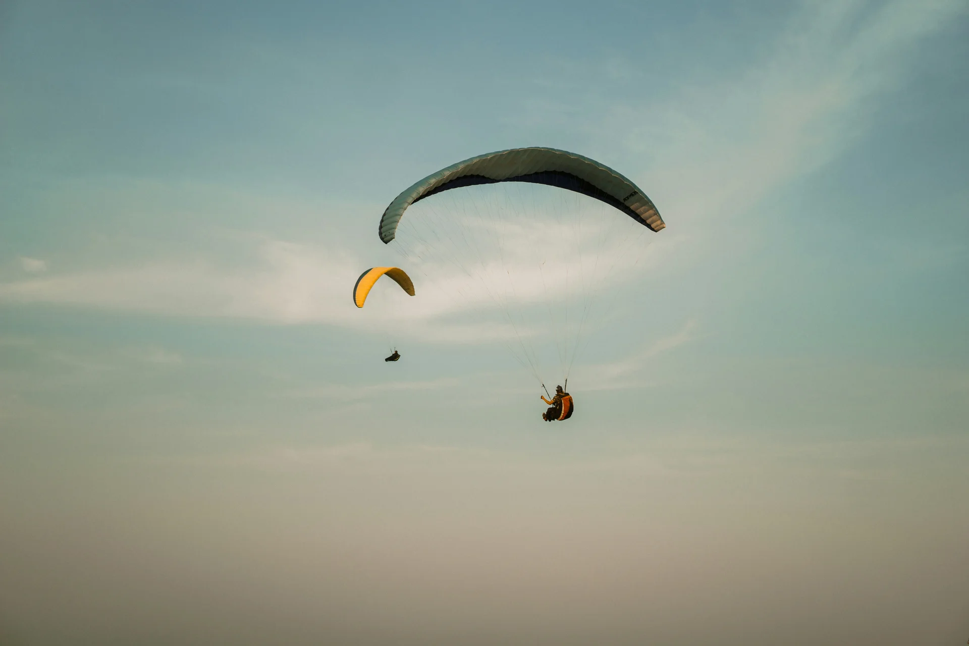 Sommer in den Bergen. In Ihrem Wanderhotel in den Dolomiten. Zwei Gleitschirmflieger schweben am Himmel bei schwachem Licht.