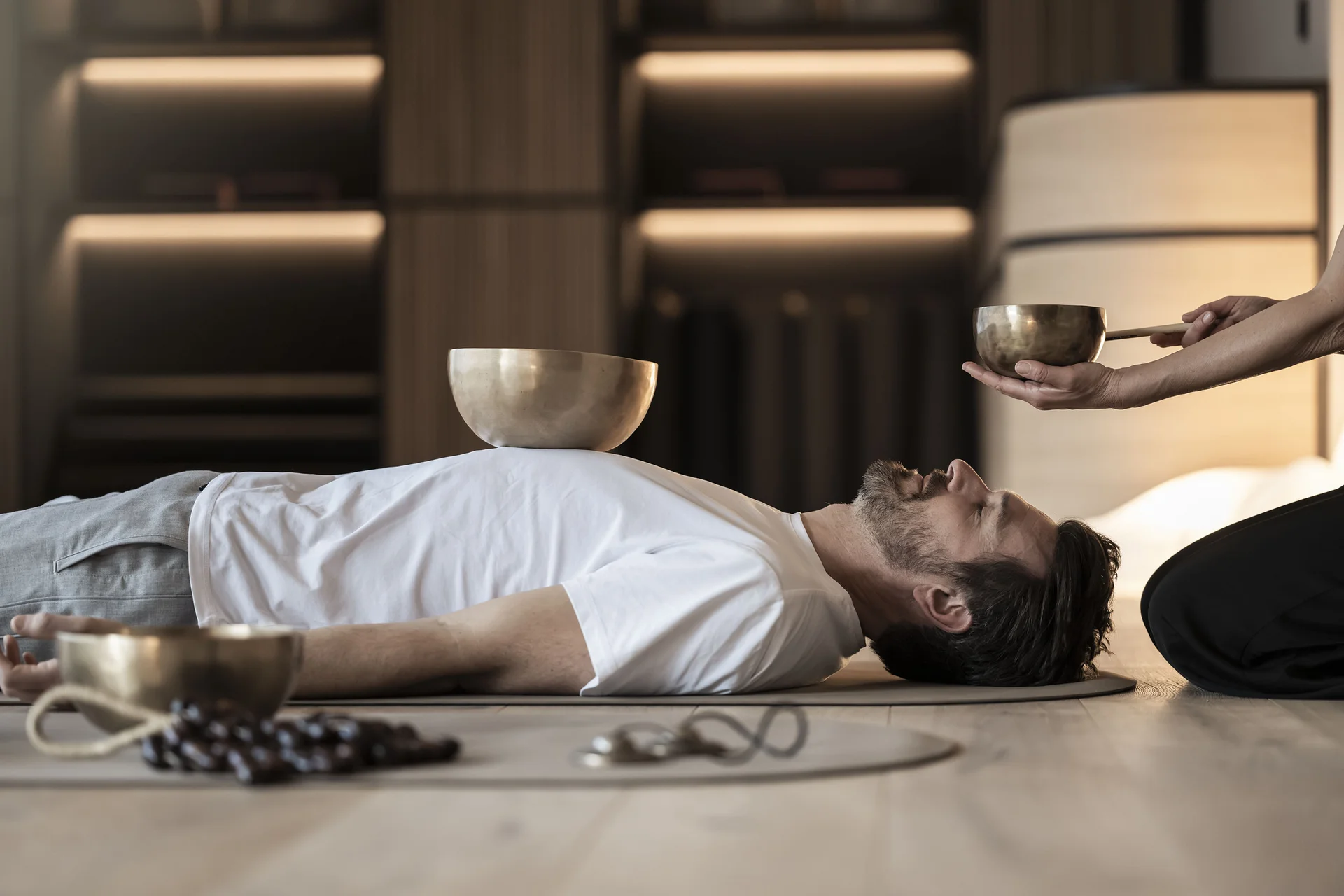 Fitness, Yoga, Outdoor-Erlebnisse: Aktivhotel in Südtirol Mann liegt für Klangtherapie mit Klangschalen auf Matte