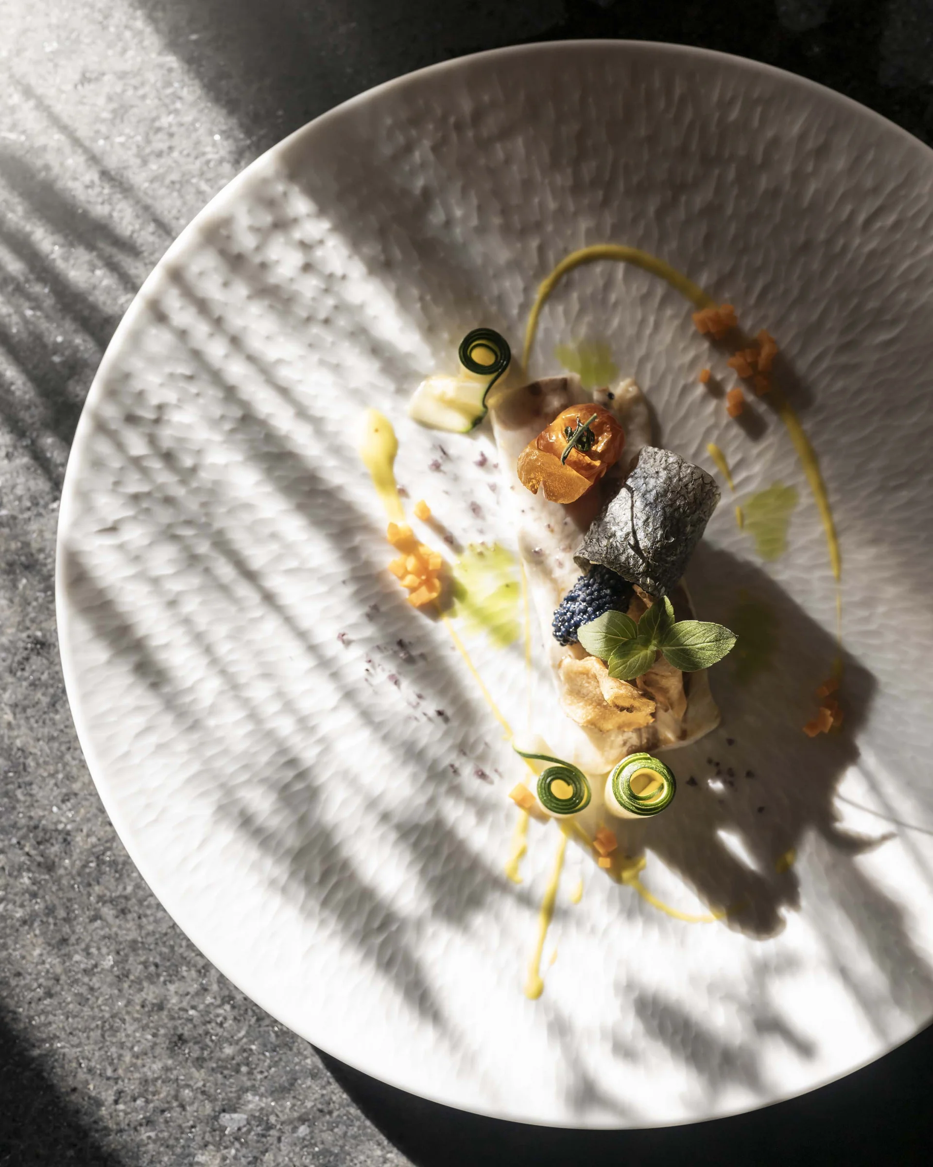 Hotel Monika in Sexten: Wohlbefinden inmitten der Dolomiten Fein angerichtetes Gourmetgericht auf weißem Teller mit Kräutern und Soße