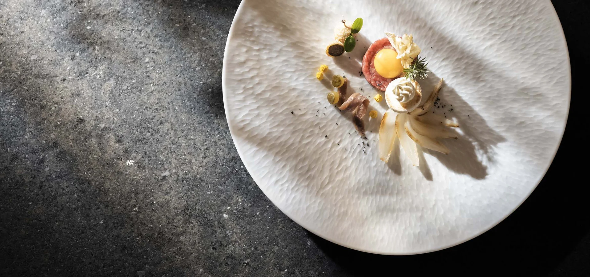 A new dimension of taste: your gourmet hotel in South Tyrol. Artfully plated dish on a white plate with dark background