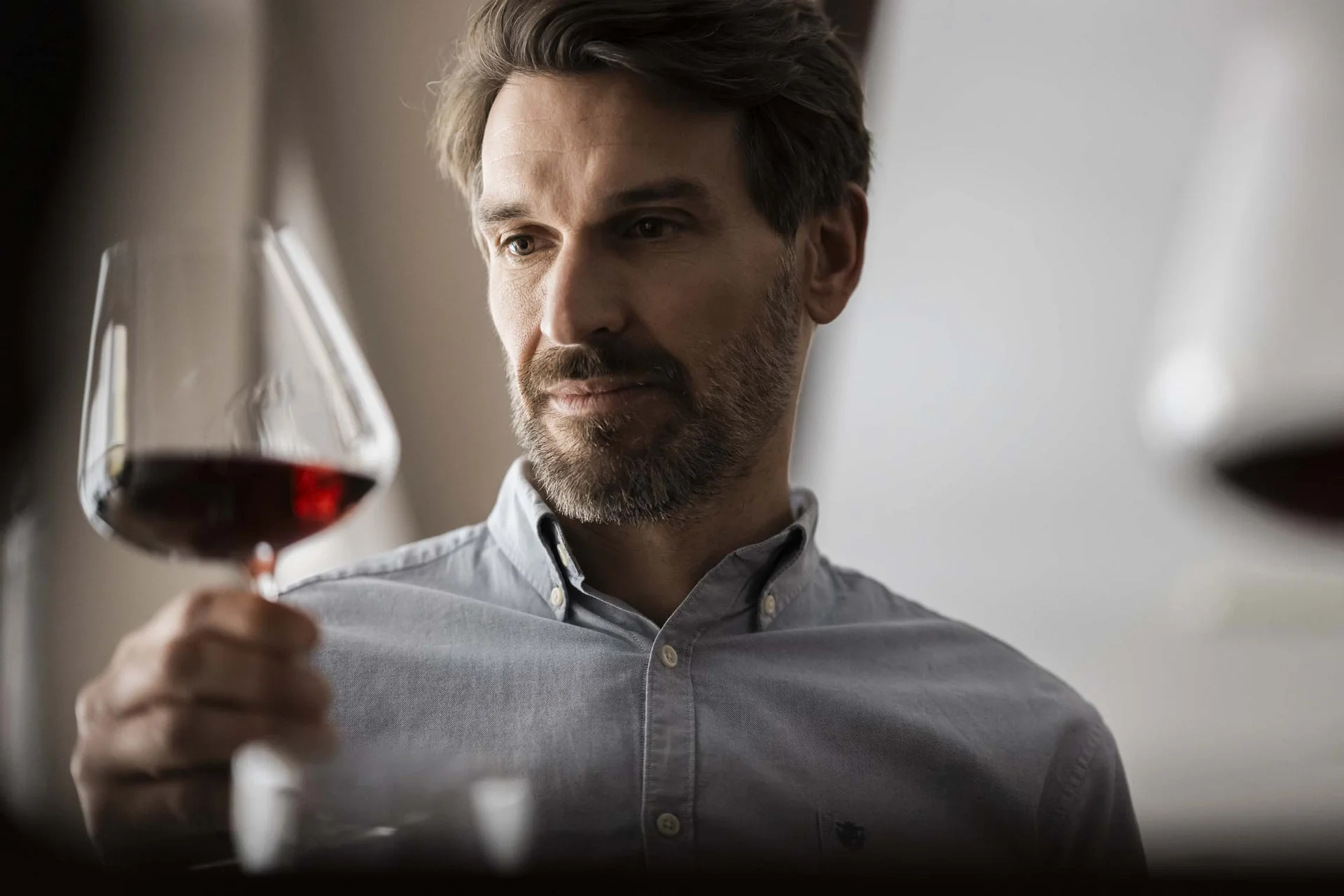 The taste of nature at your hotel with half board in South Tyrol. Man carefully observing a glass of red wine