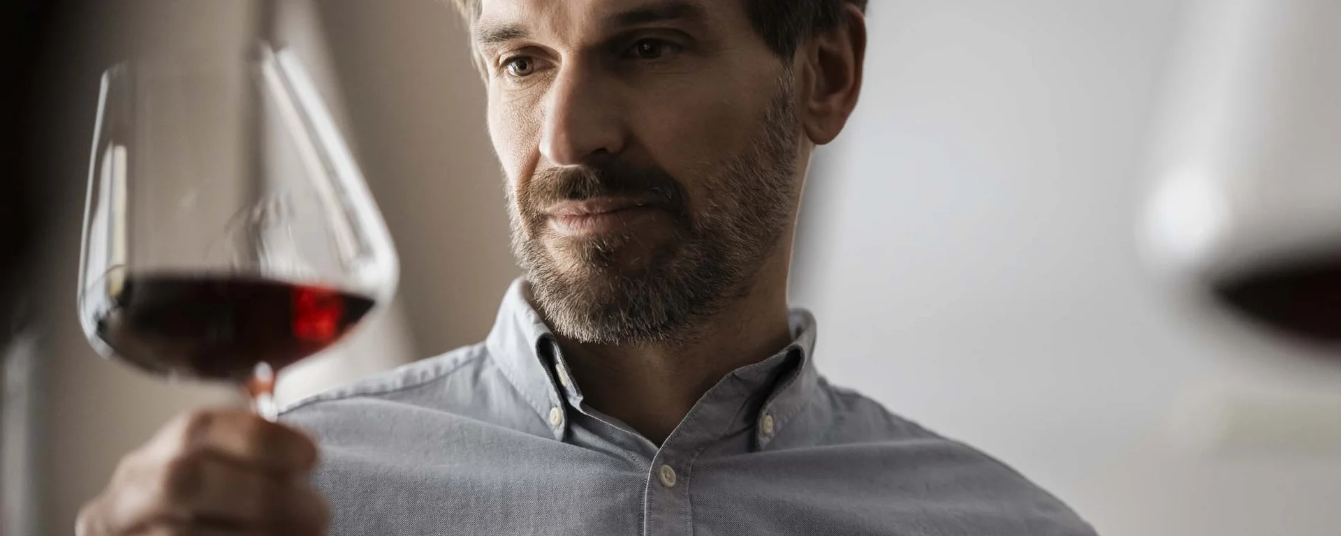 The taste of nature at your hotel with half board in South Tyrol. Man carefully observing a glass of red wine