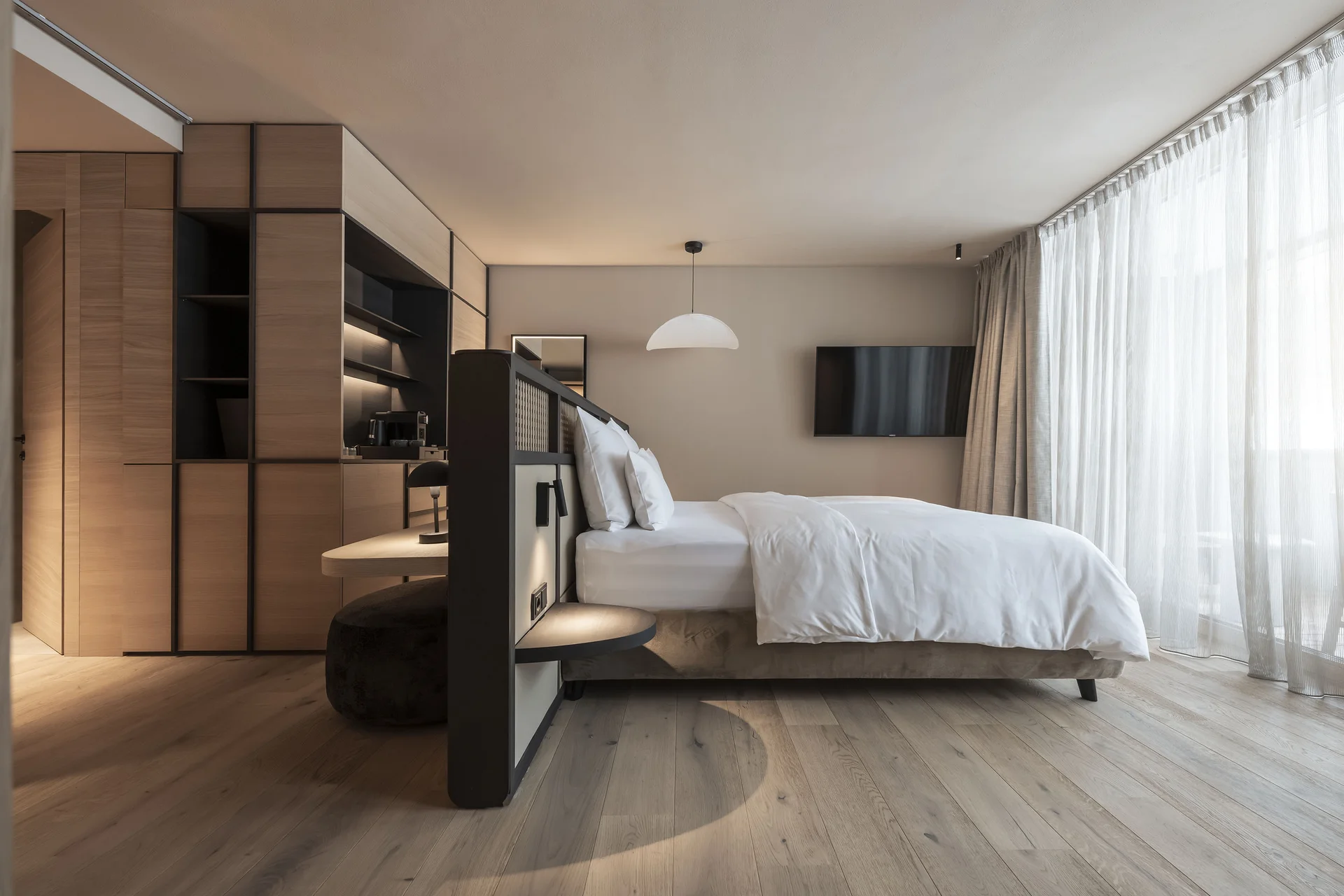 Hotel Monika: das romantische Hotel in Südtirol Modernes Hotelzimmer mit großem Bett und bodentiefen Fenstern
