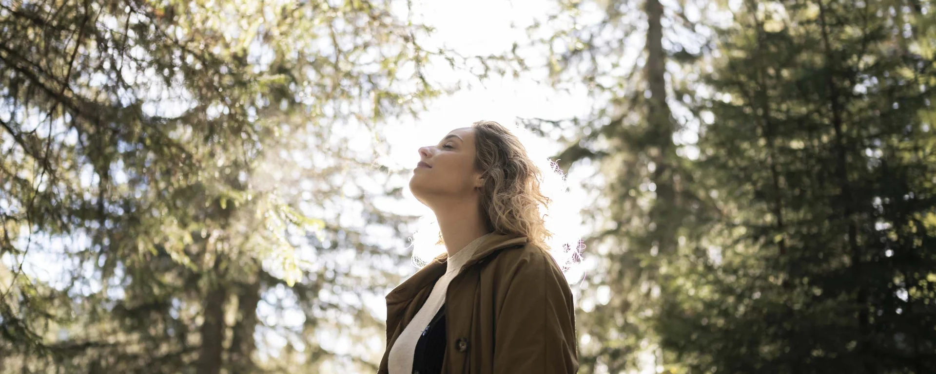 Luxury from nature: your sustainable hotel in South Tyrol. Woman enjoying nature in the forest with sunlight
