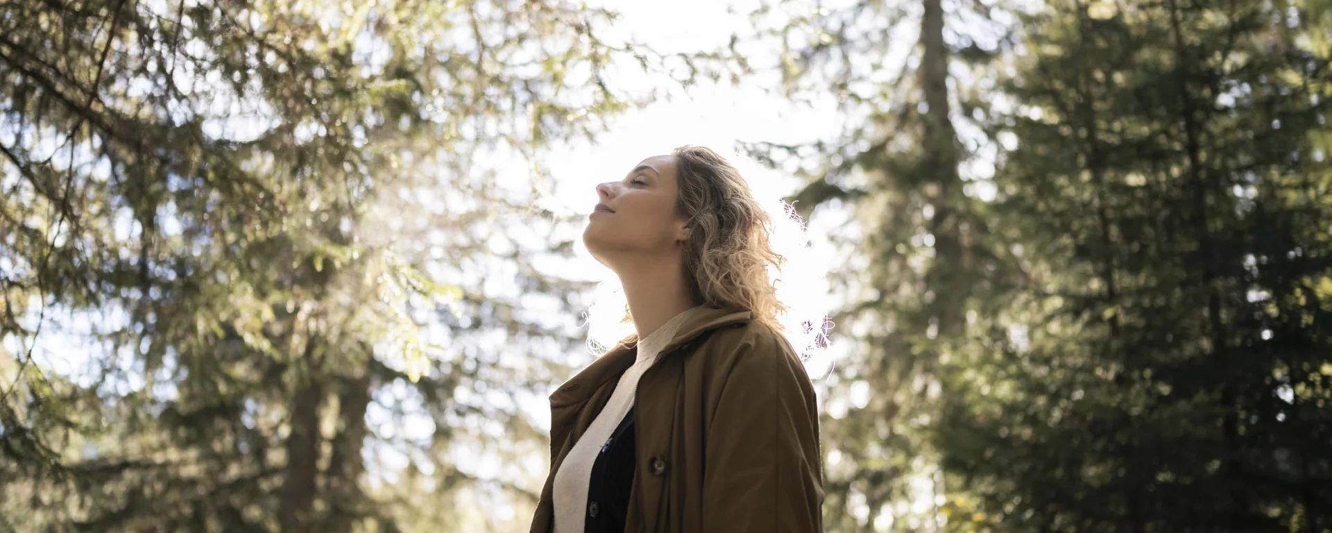 Fitness, yoga, outdoor fun: active hotel in South Tyrol. Woman enjoying nature in the forest with sunlight