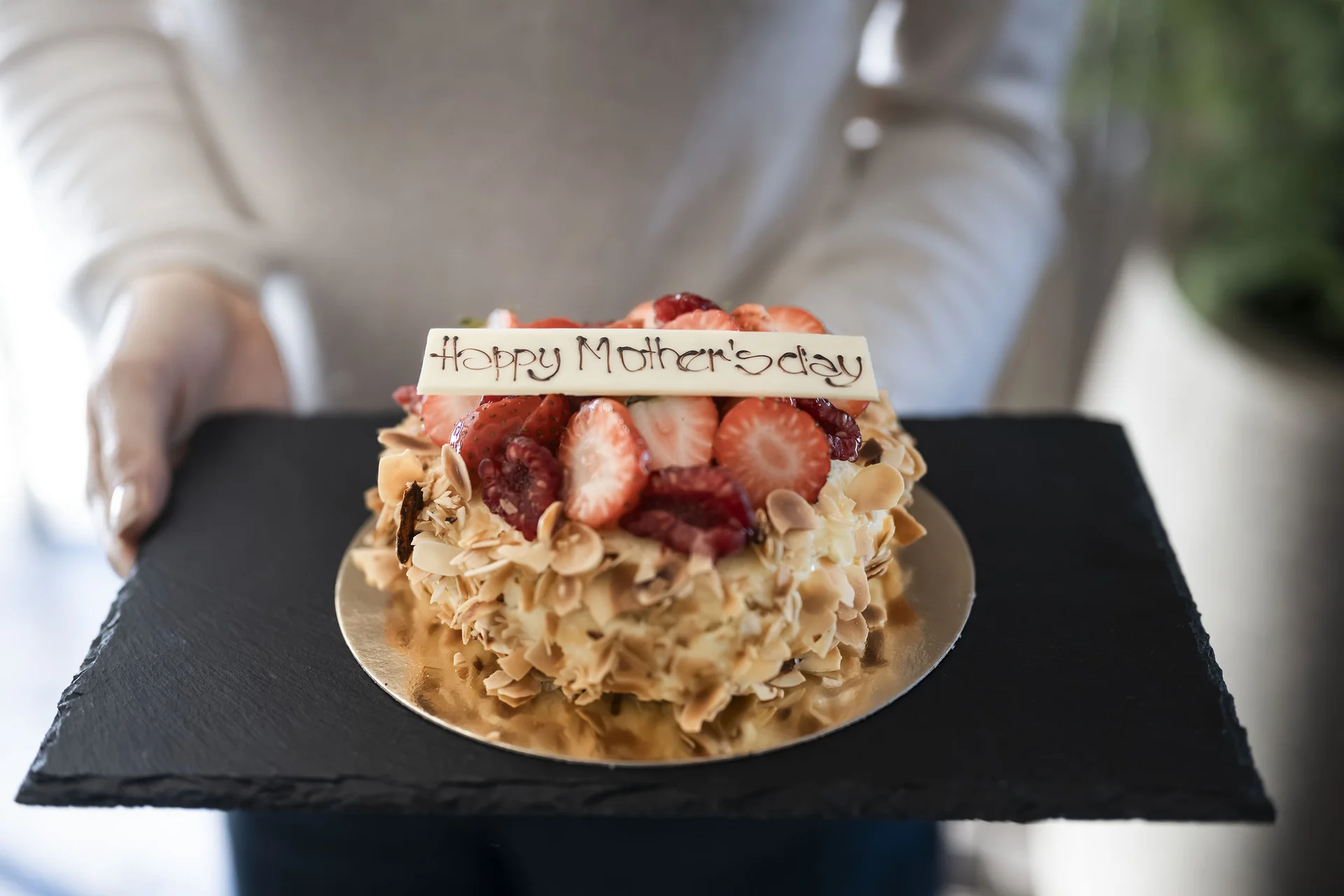 Café the bosco: ein Ort des Genusses und der Begegnung Muttertagskuchen mit Erdbeeren und Mandeln auf schwarzem Tablett