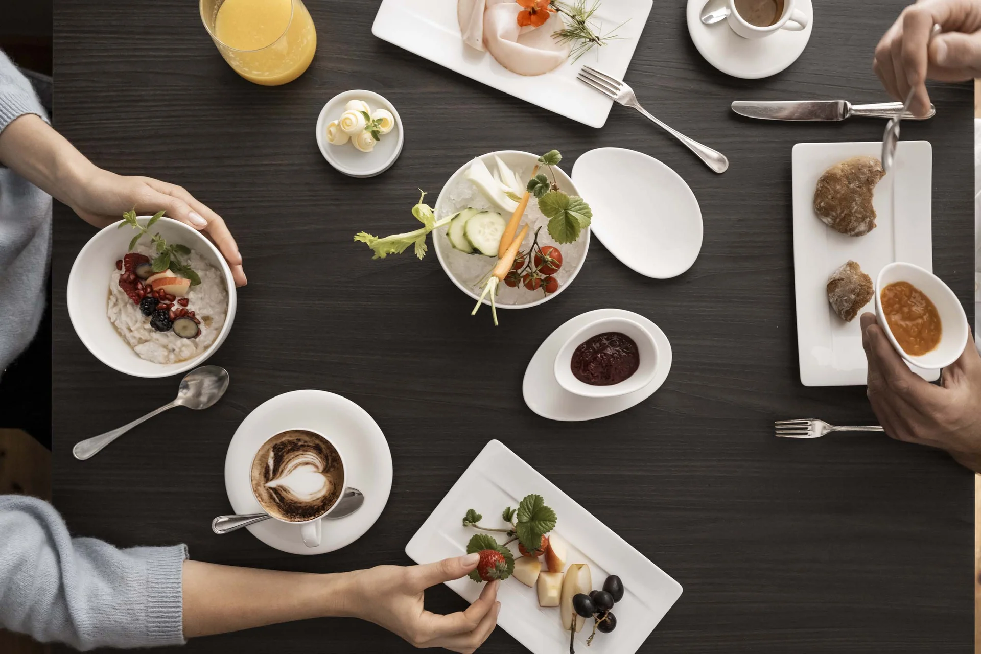 Hotel Monika in Sexten: Wohlbefinden inmitten der Dolomiten Frühstück mit Obst, Kaffee, Saft und Brot auf einem dunklen Tisch