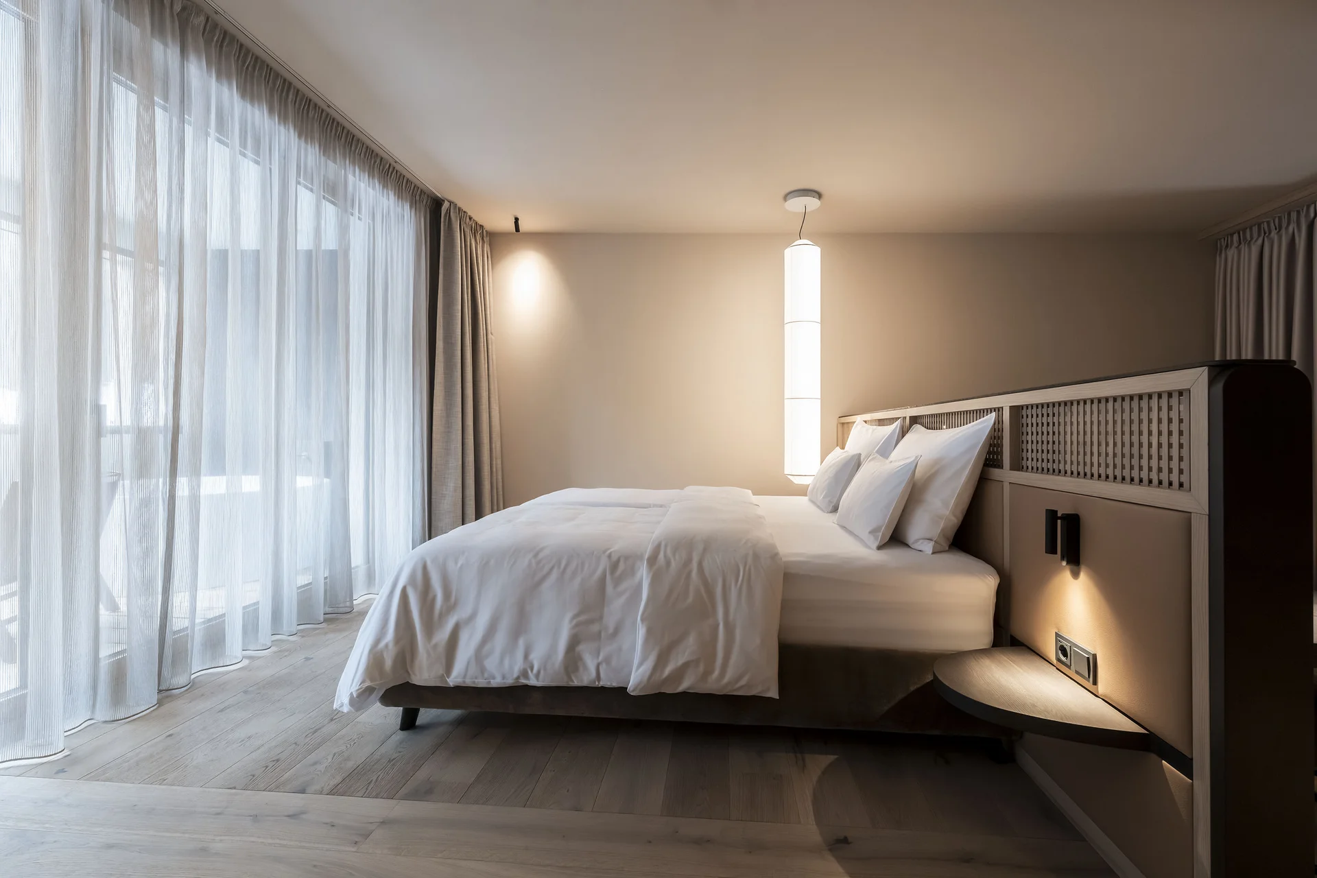 Das Wellnesshotel für den Urlaub mit Hund in Südtirol Modernes Schlafzimmer mit großem Bett und bodentiefen Vorhängen
