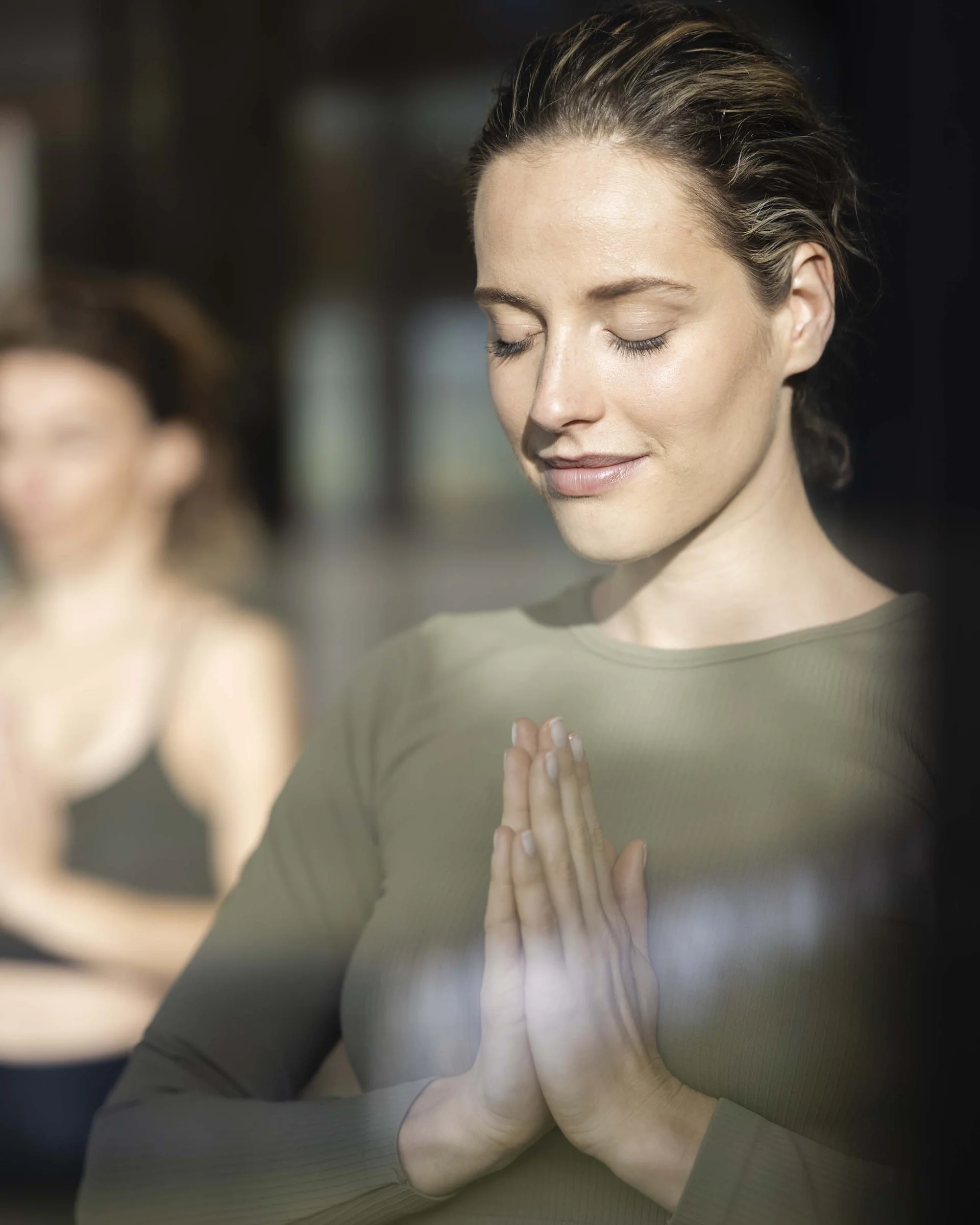 Hotel Monika in Sexten: Wohlbefinden inmitten der Dolomiten Frau in grüner Kleidung meditiert mit gefalteten Händen und geschlossenen Augen