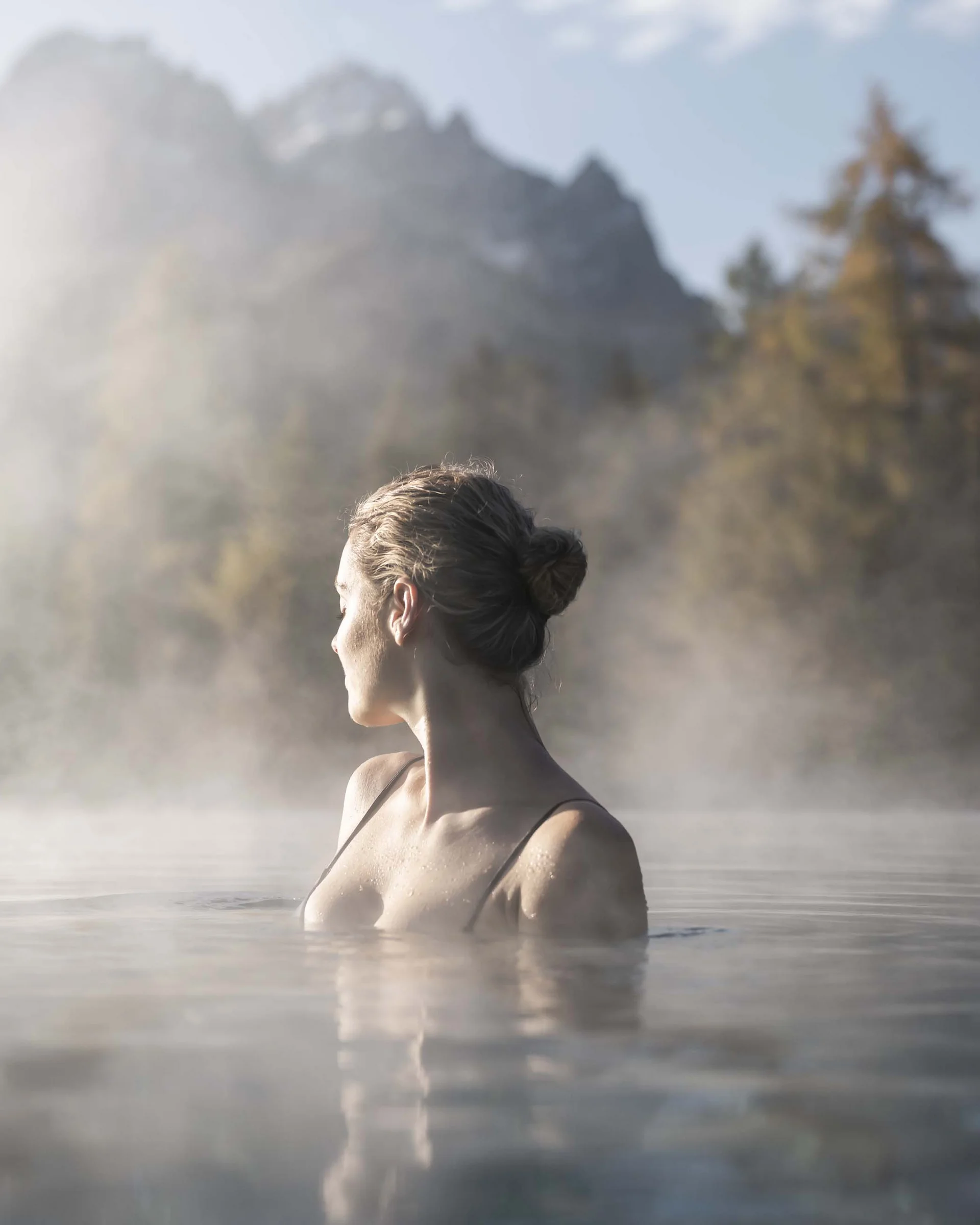 Hotel Monika in Sexten: Wohlbefinden inmitten der Dolomiten Frau entspannt im heißen Thermalwasser mit nebeligem Bergpanorama im Hintergrund
