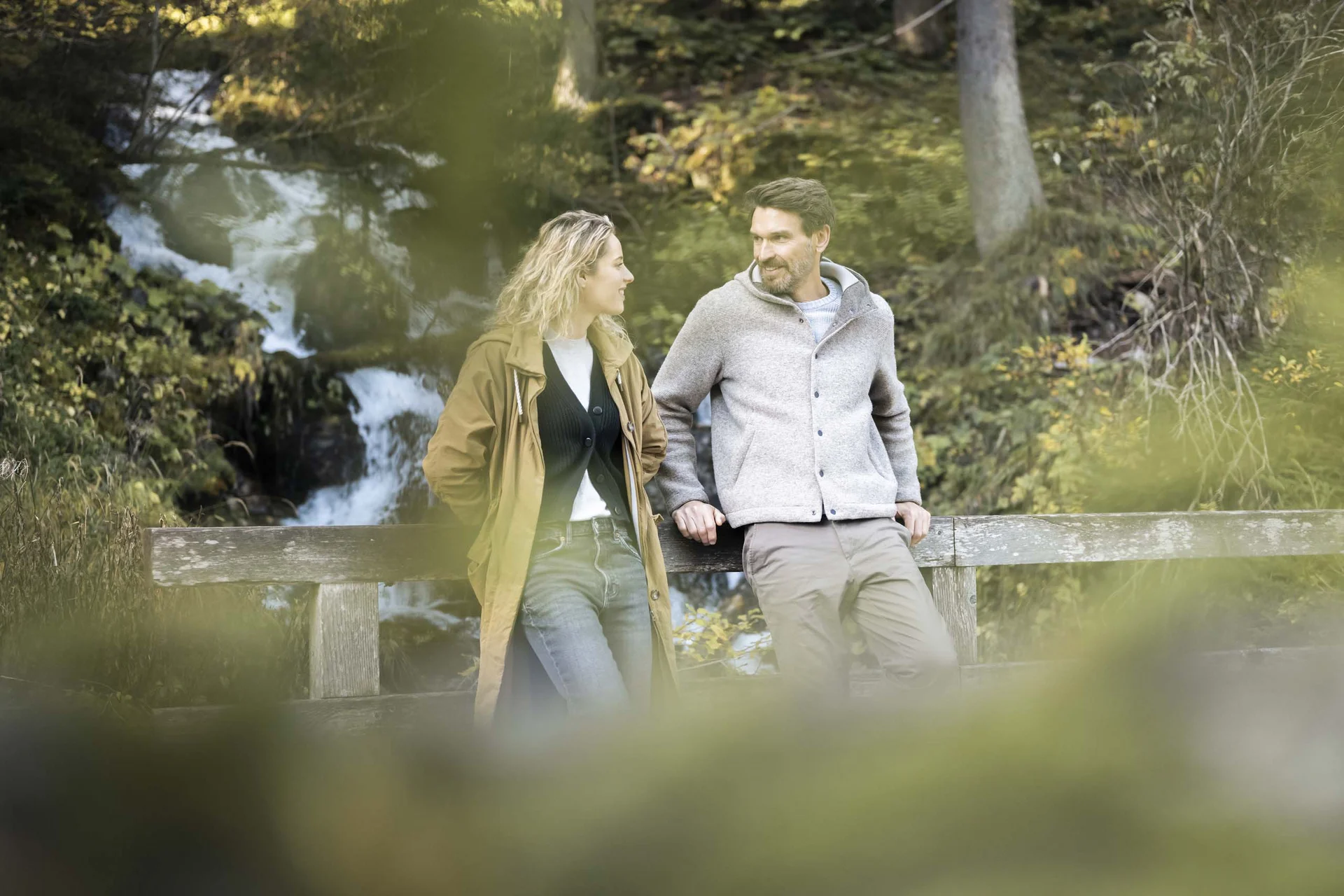 Hotel Monika: eine neue Dimension von Luxus Paar steht auf Brücke vor Wasserfall im Wald