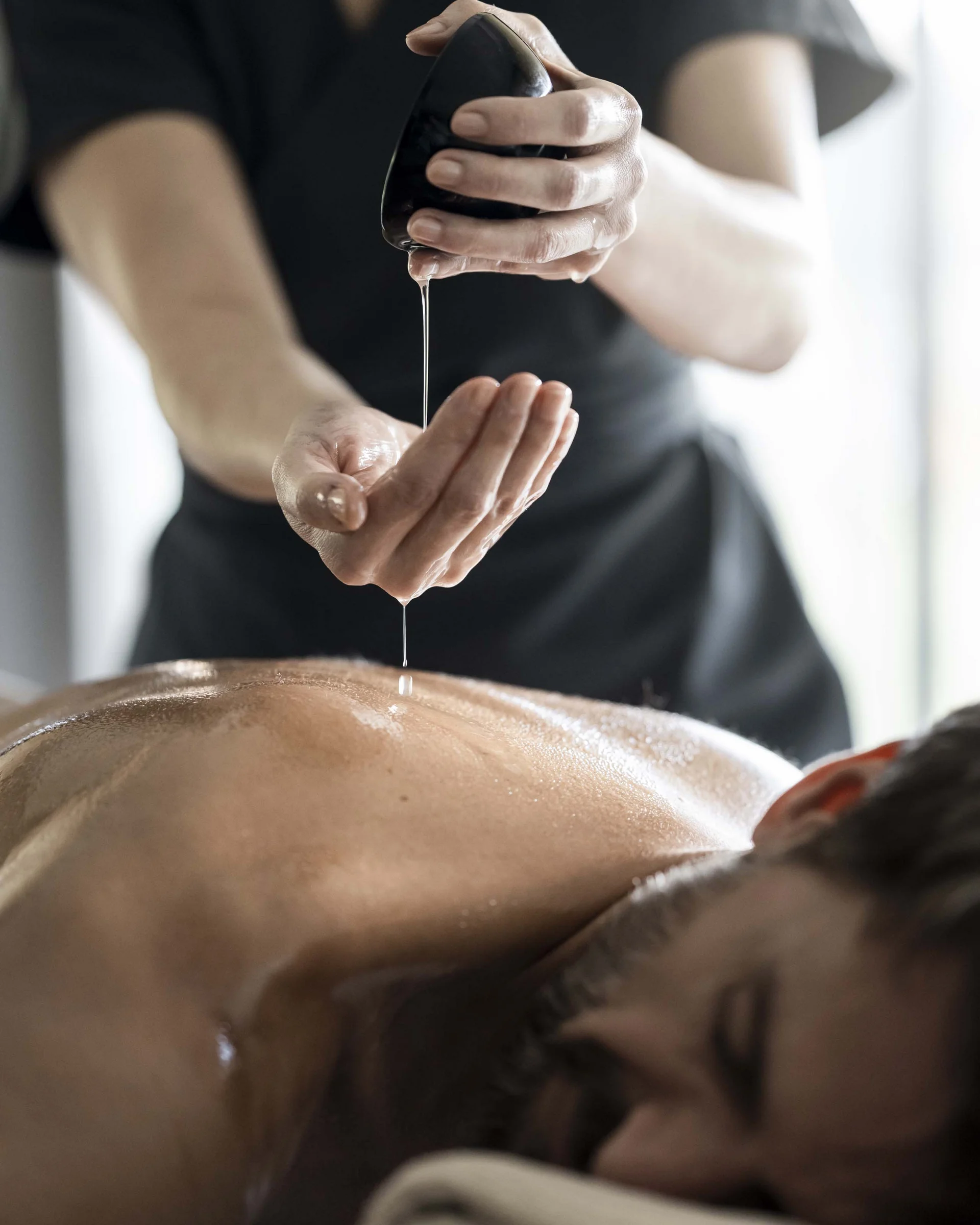 A new dimension of well-being: your wellness hotel in Sexten Man receiving massage with oil dripping from a stone