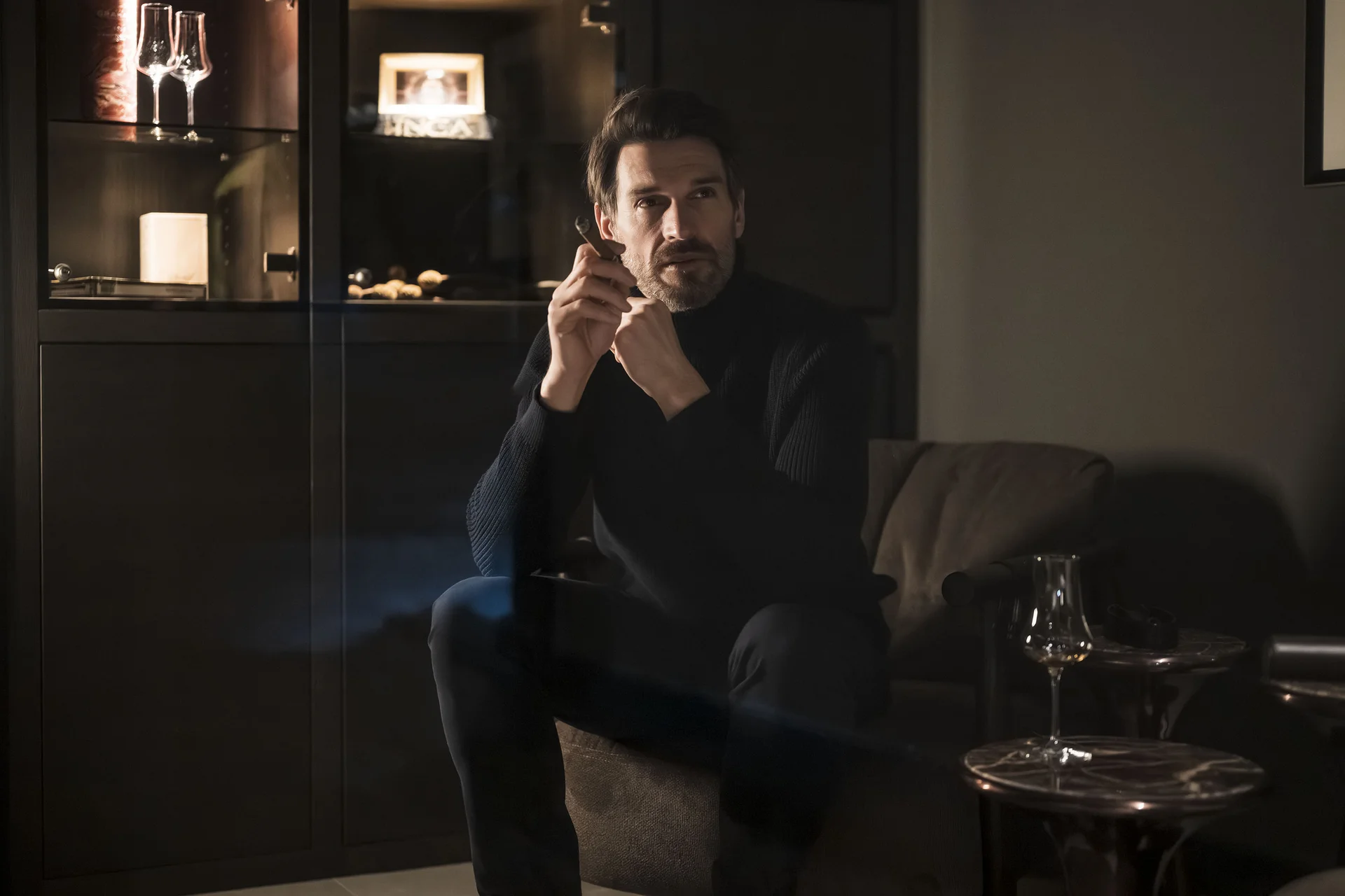 Hotel Monika in Sexten: Wohlbefinden inmitten der Dolomiten Mann in dunklem Pullover sitzt nachdenklich in gemütlichem Raum