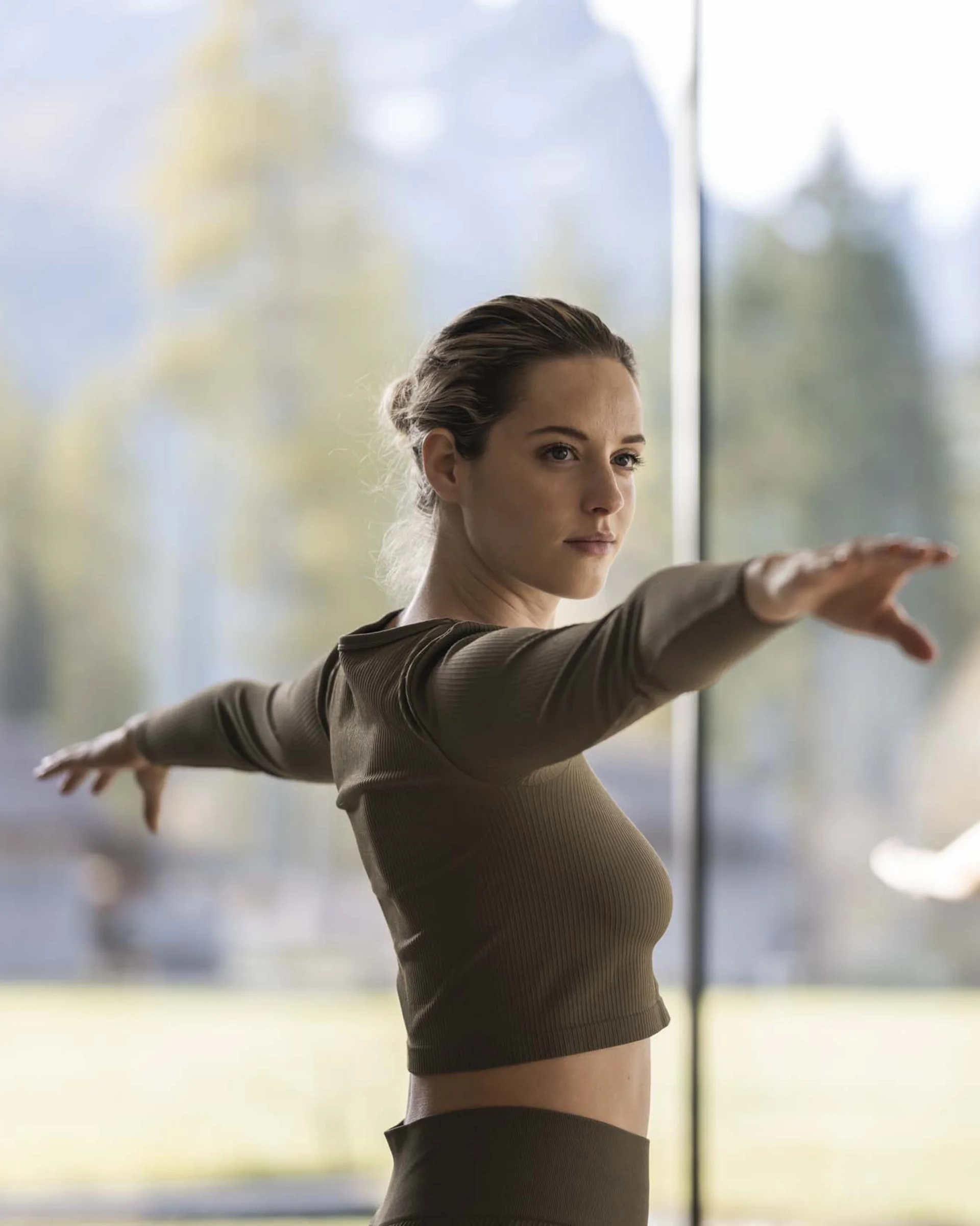 Hotel Monika in the Dolomites – with pools and spa area Two women doing yoga pose with arms extended in bright room