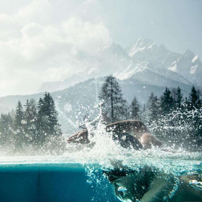 Ein Mann schwimmt im Outdoor-Pool