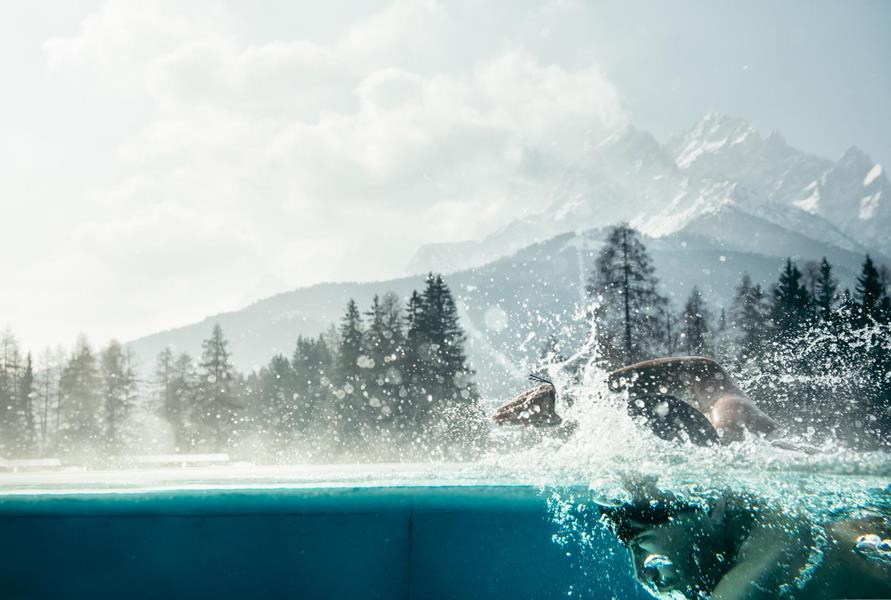 Ein Mann schwimmt im Outdoor-Pool